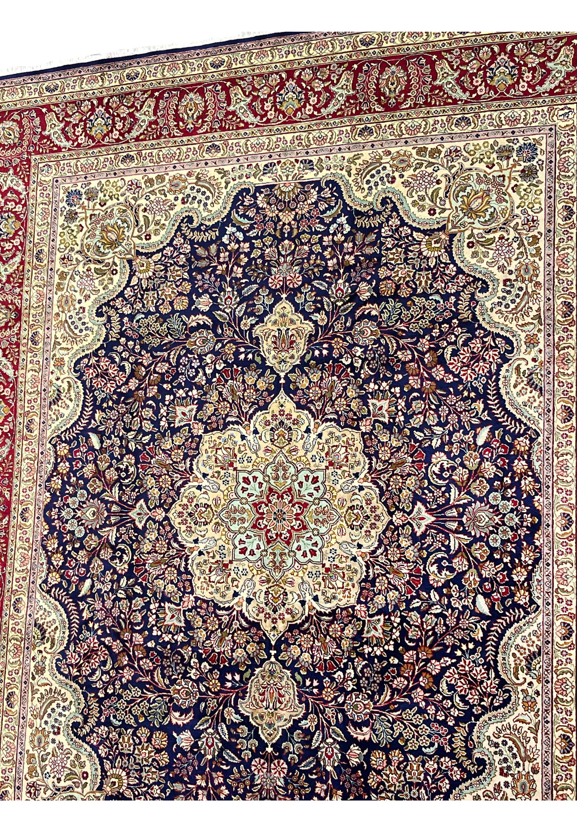 Upper field detail of Persian Tabriz rug featuring dense floral pattern, navy blue ground, ivory highlights, and precise hand knotted detail