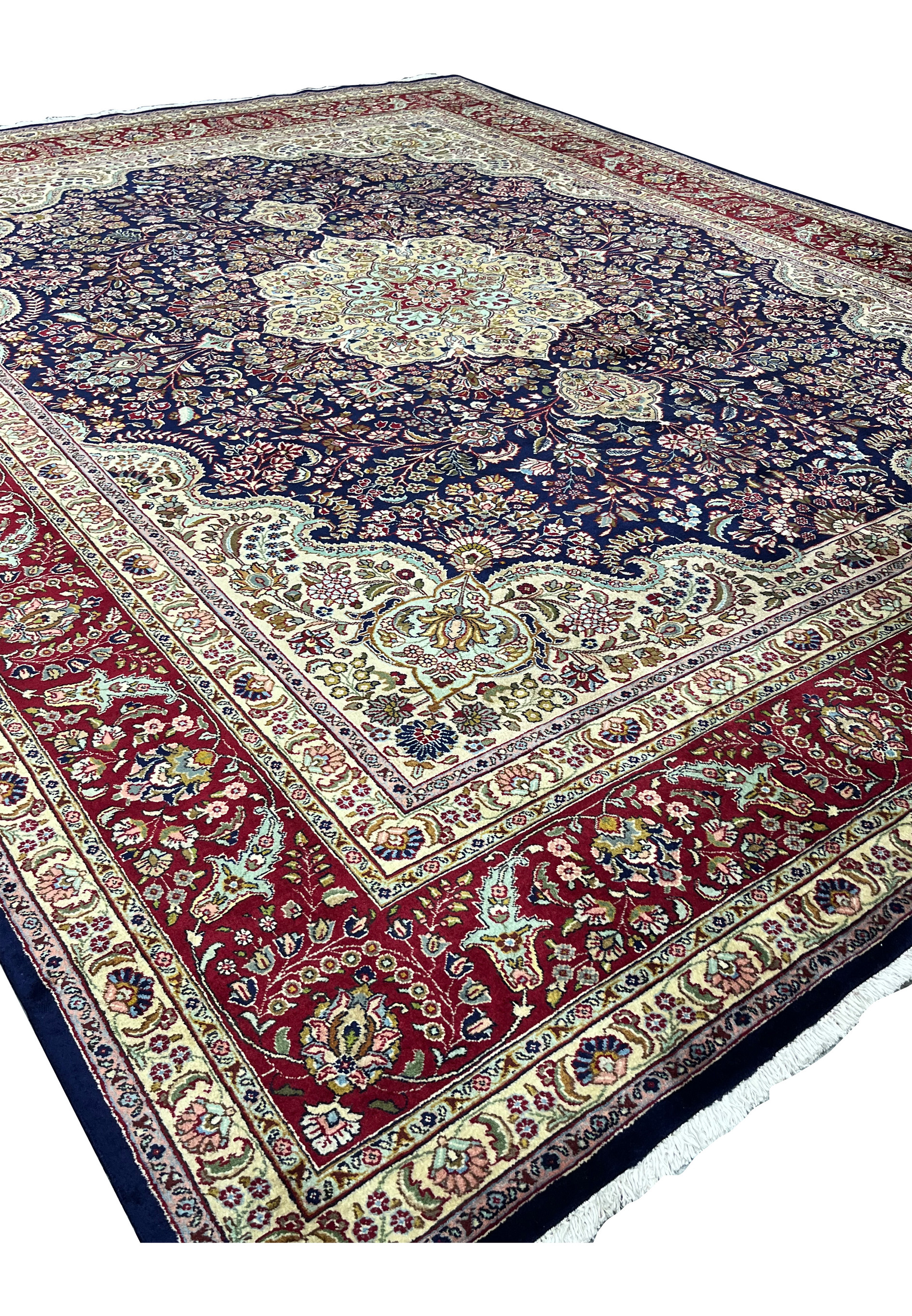 Angled view of an 11'2 x 14'4 Persian Tabriz rug with deep navy field, intricate floral vines, ivory detailing, and rich red border