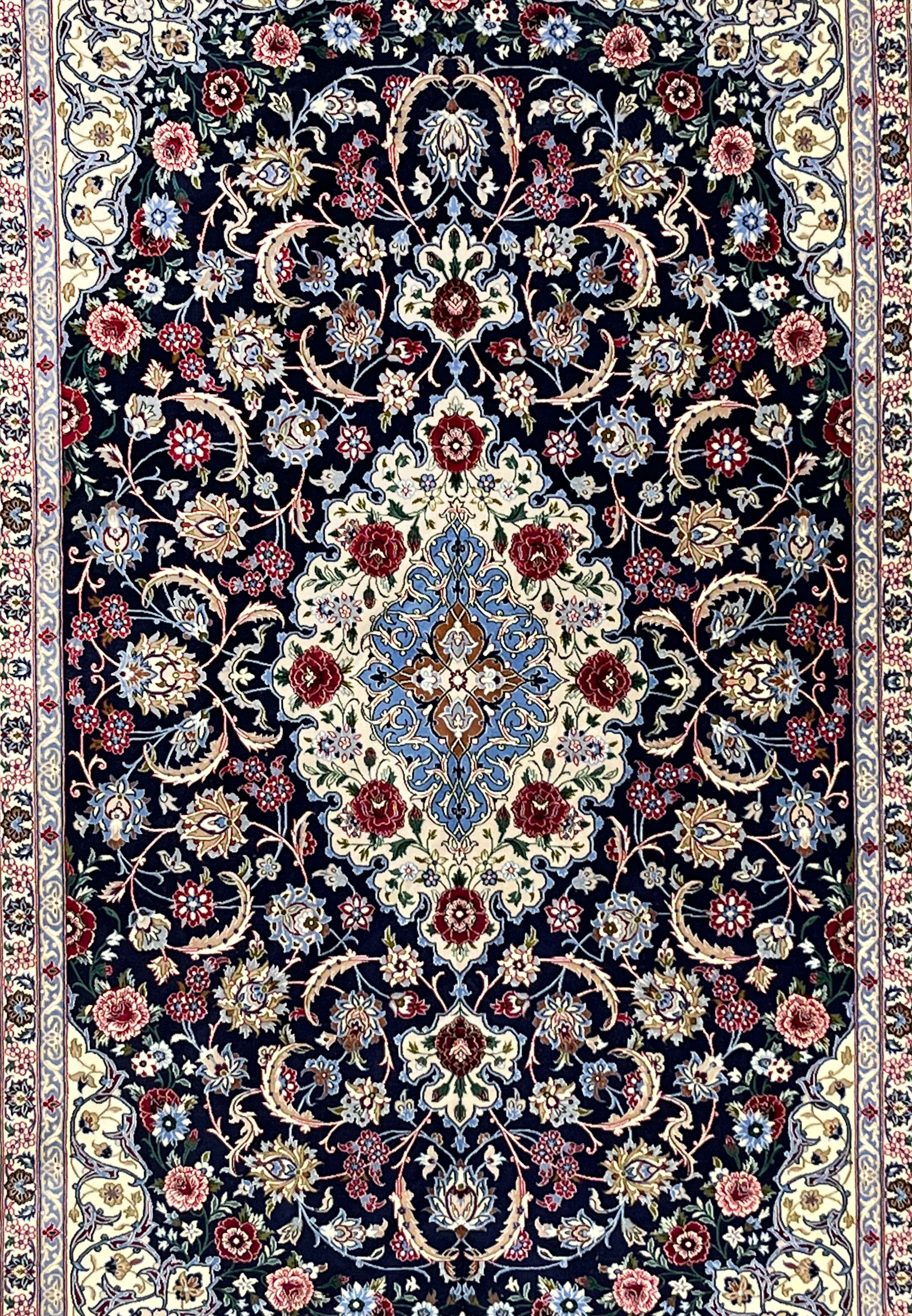 Central field of Persian Isfahan rug featuring ivory medallion, light blue arabesques, burgundy floral accents, and dense fine knot structure