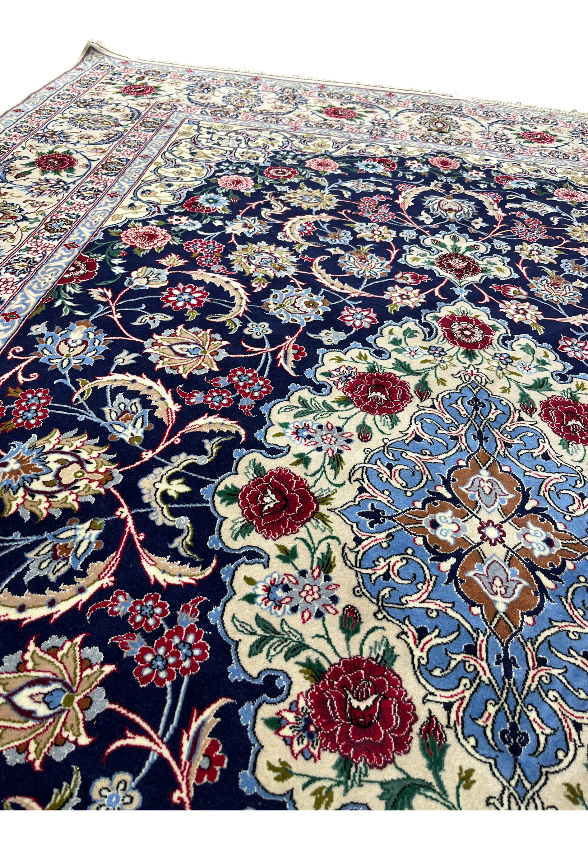 Field closeup of super fine Isfahan rug showing navy wool ground, silk floral motifs, and exceptionally tight knot structure