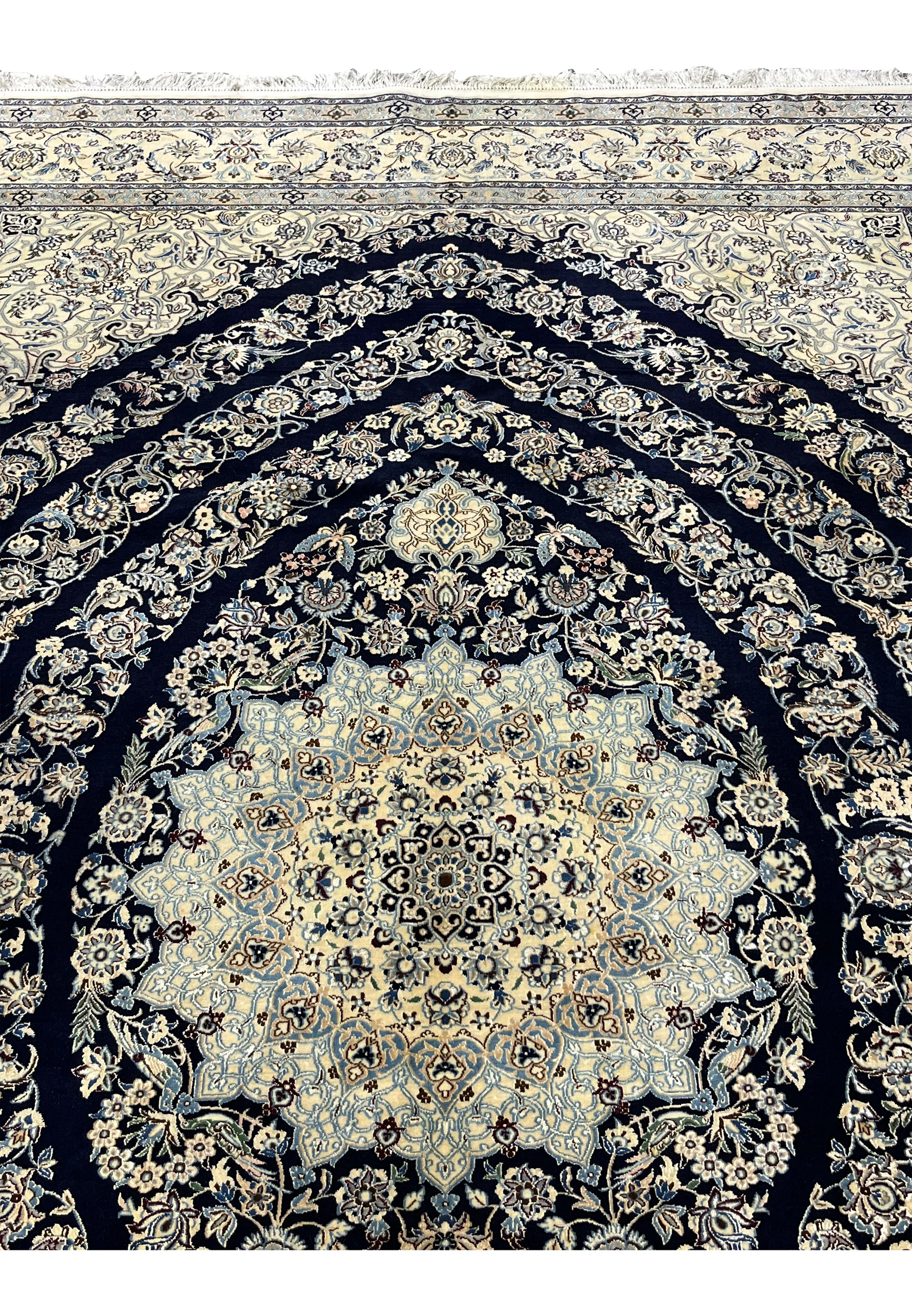 Upper section of Persian Nain 6 La rug showing navy field with scrolling floral vines and silk highlights near the top border