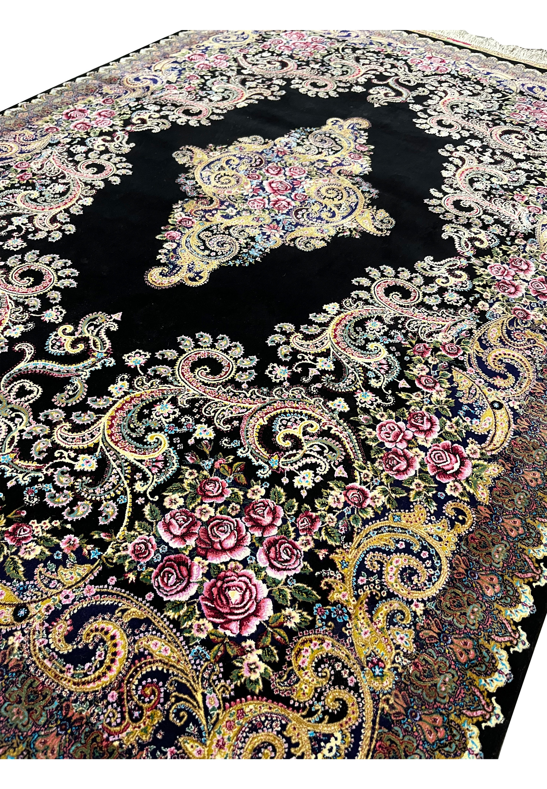 Angled view of a signed Persian Qum silk rug highlighting silk sheen, fine knotting, and detailed floral design