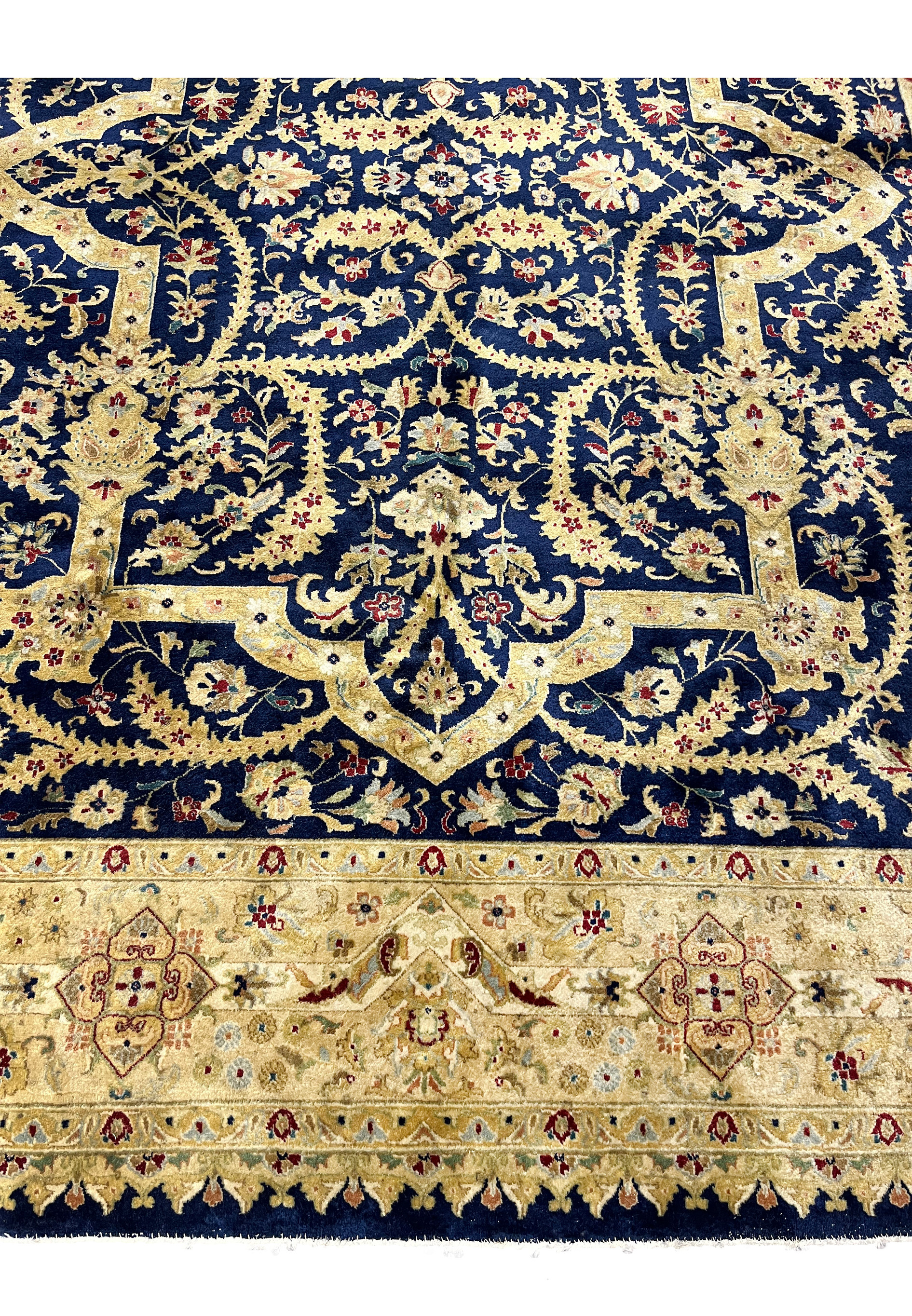Lower border close-up of a worn Indian Agra rug showing antique gold tones, floral cartouches, softened reds, and visible age-related patina