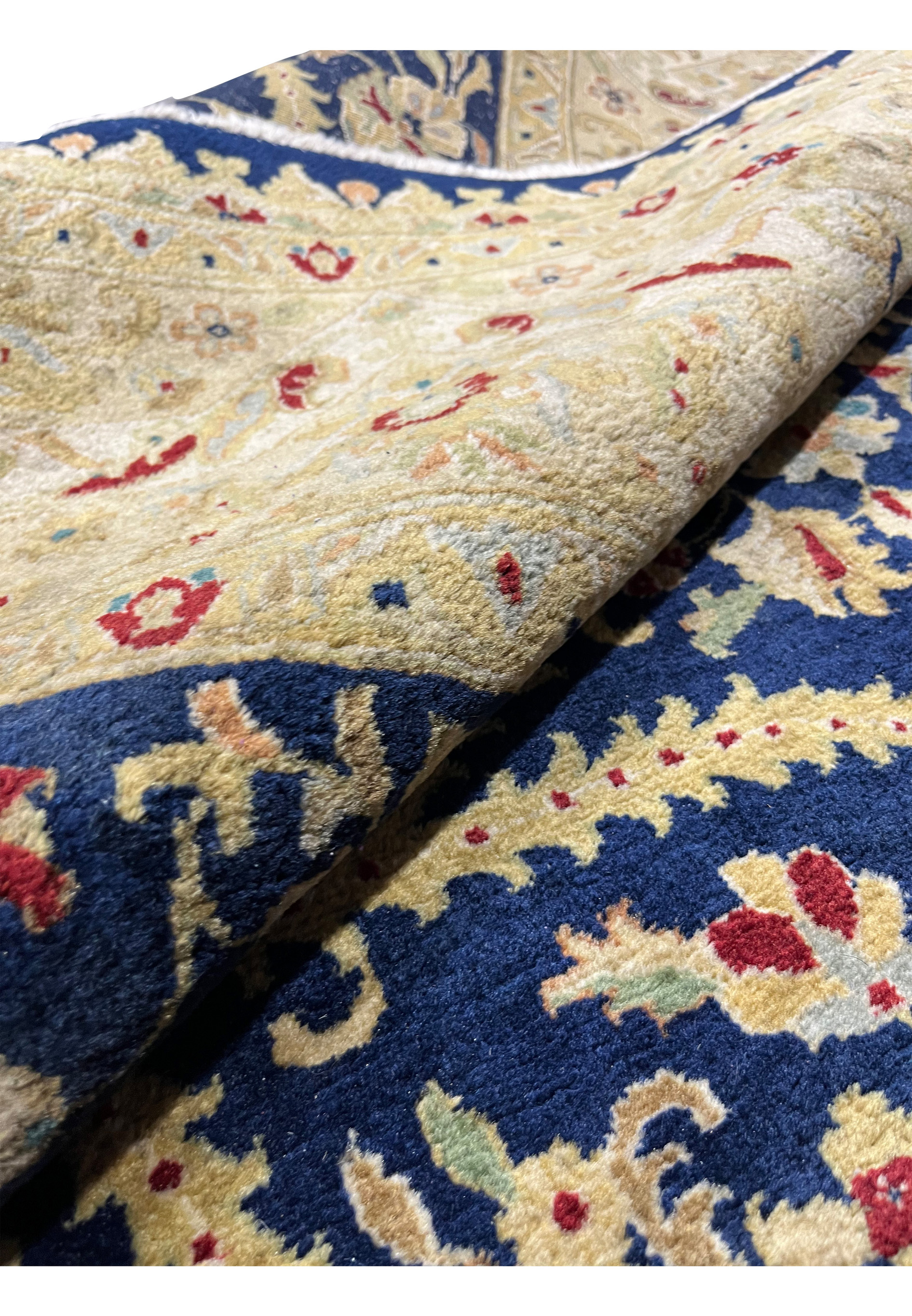 Rolled view of a distressed Oriental Agra rug showing thickness, wool texture, aged coloration, and flexible structure despite visible wear