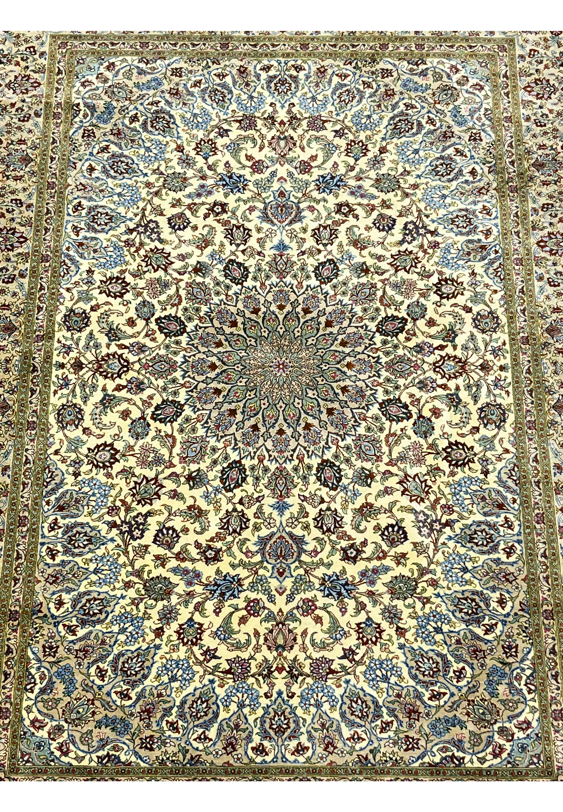 Midfield detail of a signed Persian Qum pure silk rug revealing dense floral motifs, flowing vine patterns, and crisp color transitions on an ivory background.