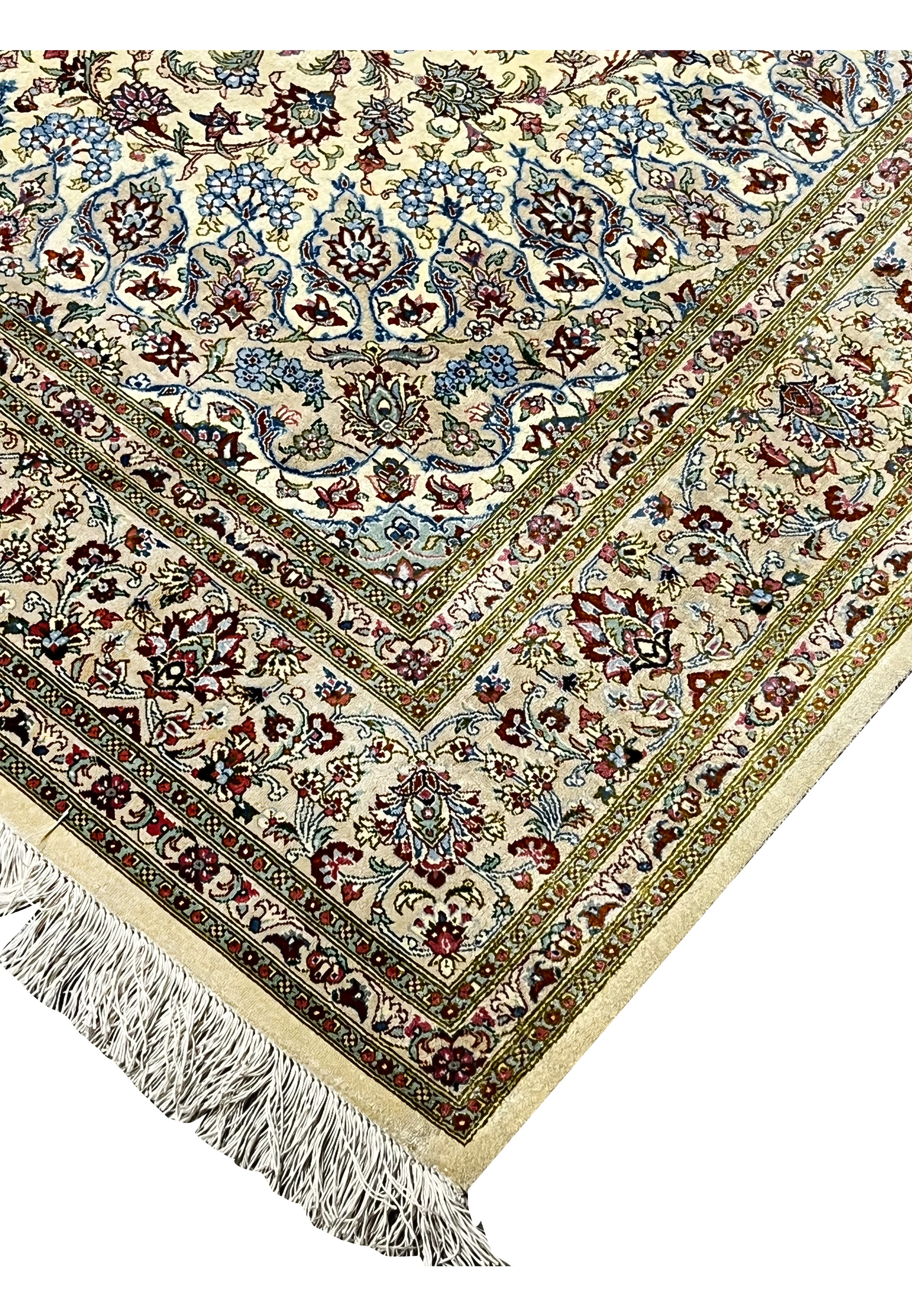 Close-up of the corner edge of a signed Persian Qum pure silk rug showing tightly knotted ivory silk pile, floral motifs, and neatly finished fringe.