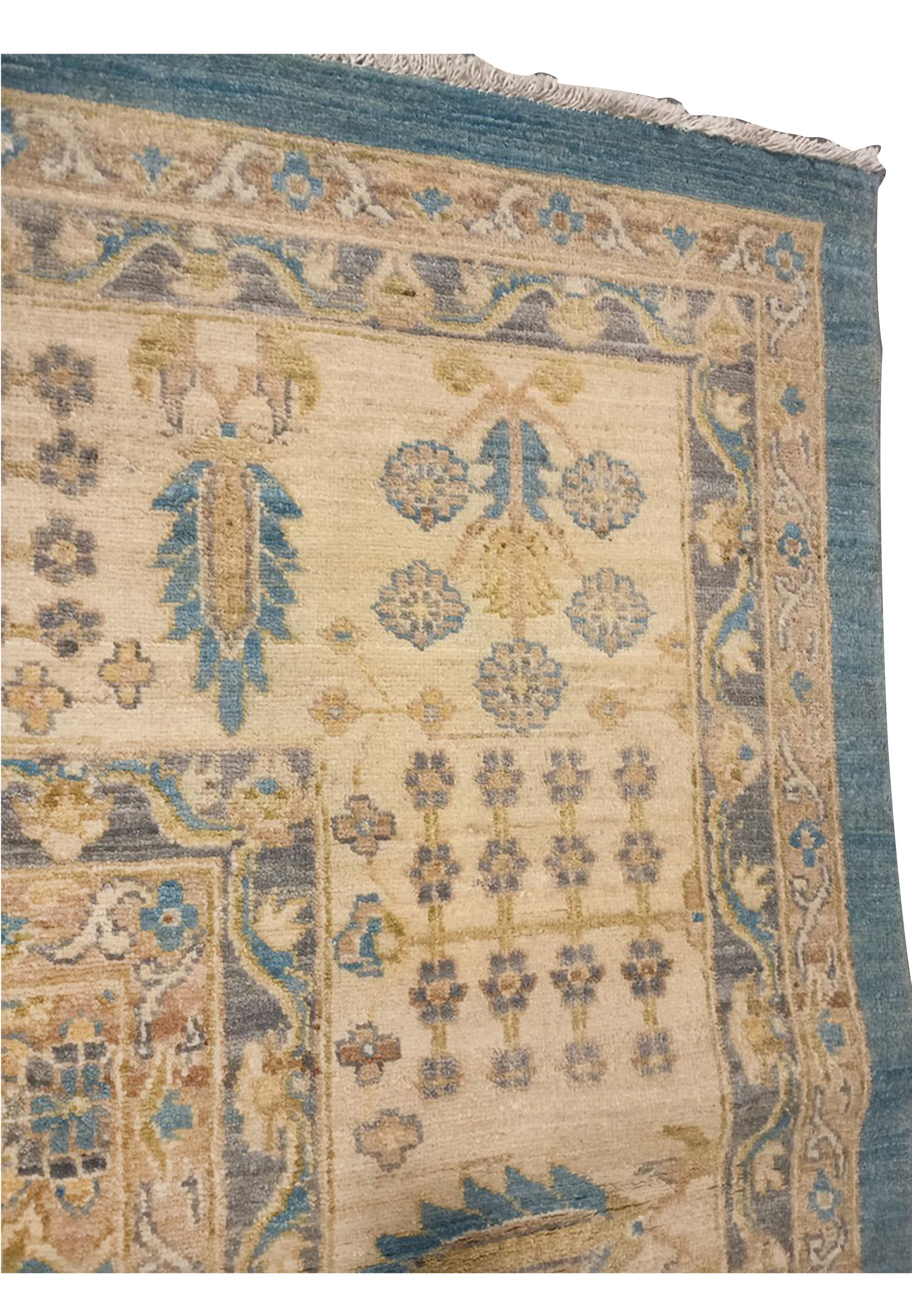 Close up of the border on a light blue Chobi Peshawar rug featuring floral motifs, cream background, muted blue accents, and finely knotted wool detail