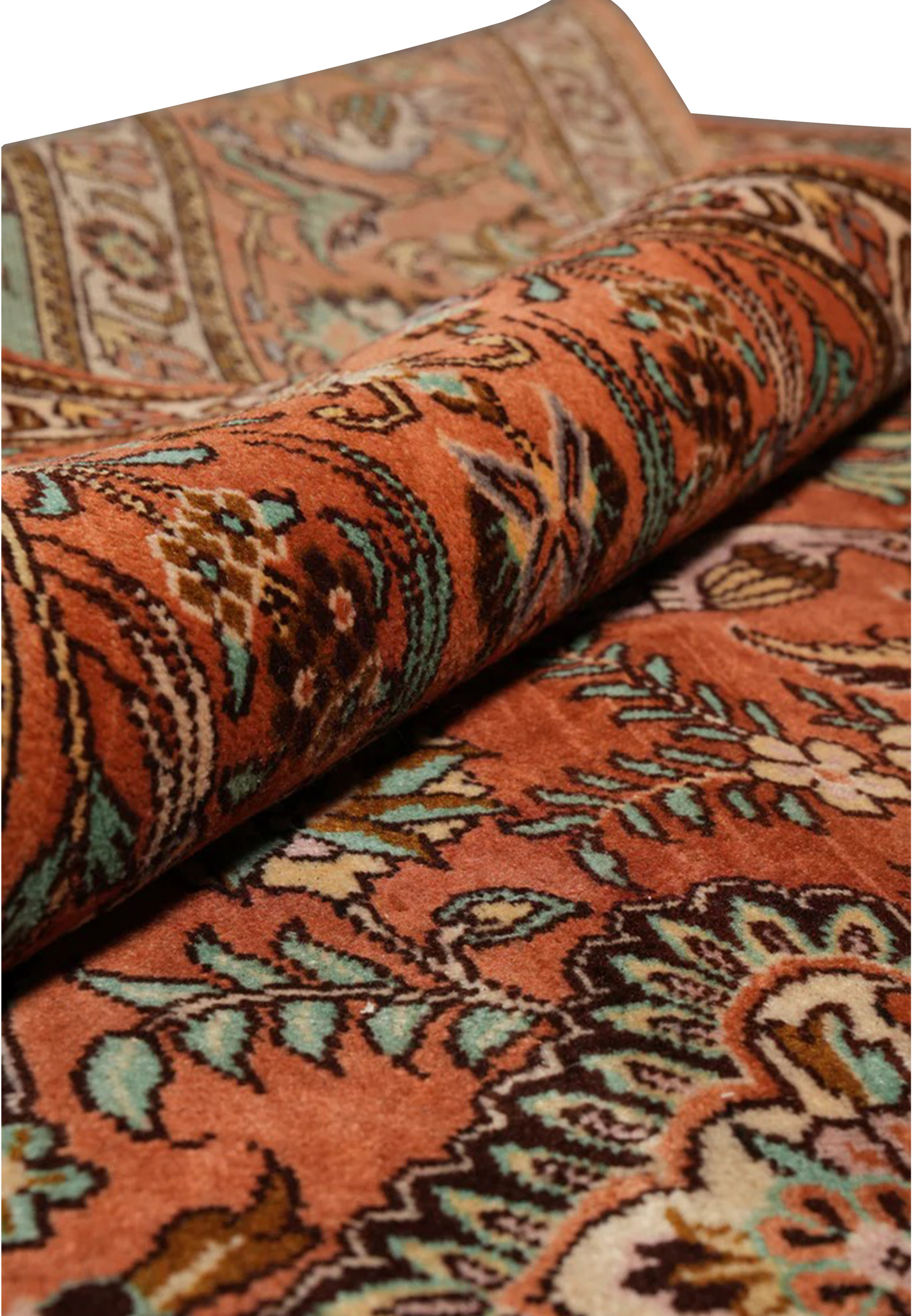 Rolled view of a signed Paradies Persian Tabriz rug highlighting soft kork wool texture, warm terracotta tones, garden motifs, and flexible hand-knotted structure