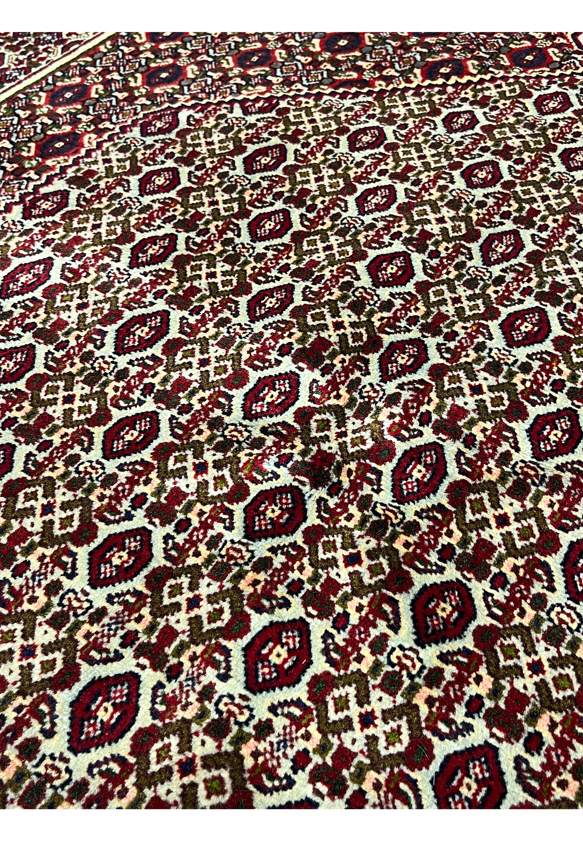 Color close-up of medallion area in Persian Senneh rug showing burgundy, ivory, blush pink, olive green, and dark brown detailing