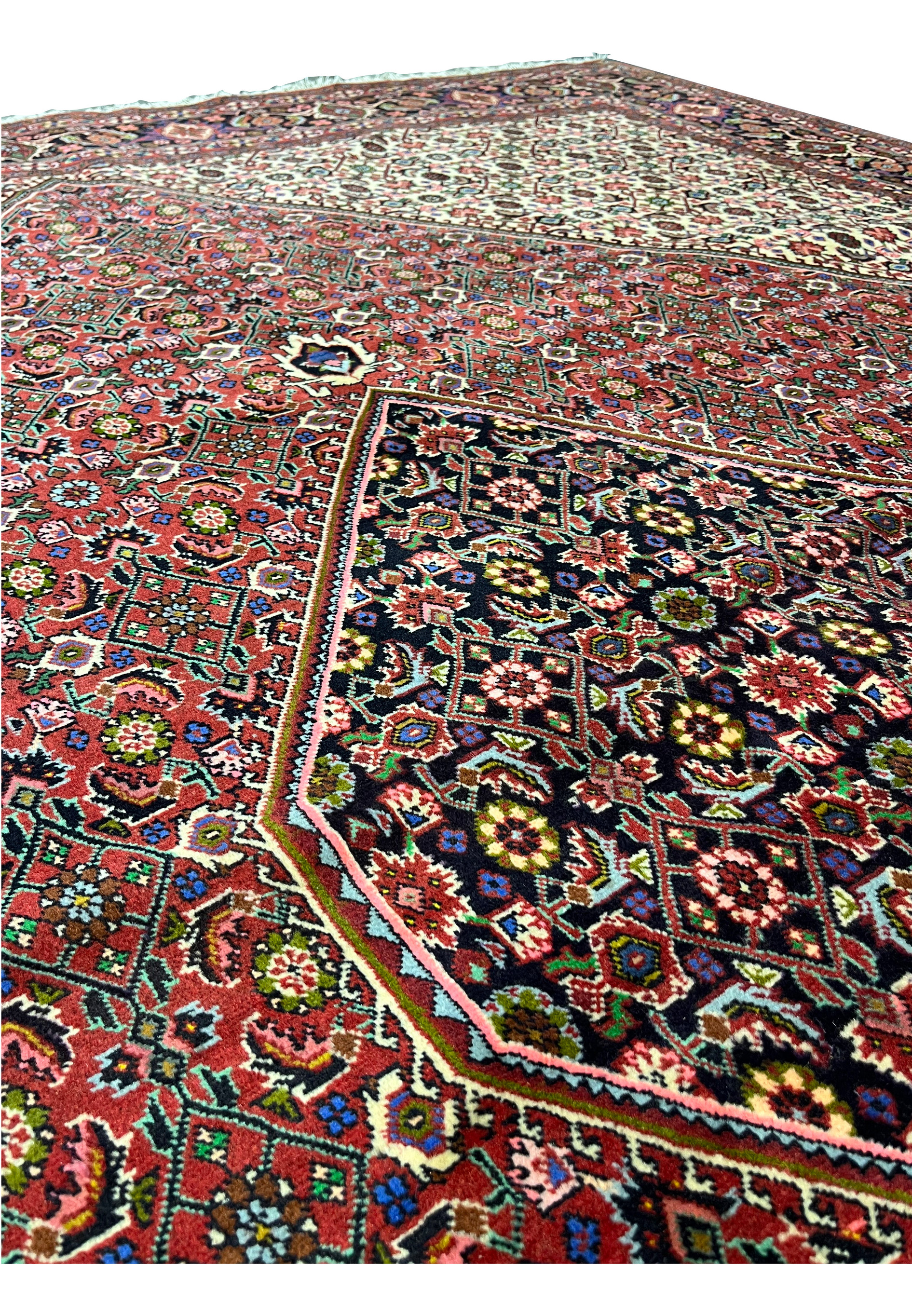 Medallion close-up of Persian Bijar rug featuring layered diamond geometry, deep red tones, dark outlines, and finely articulated wool details