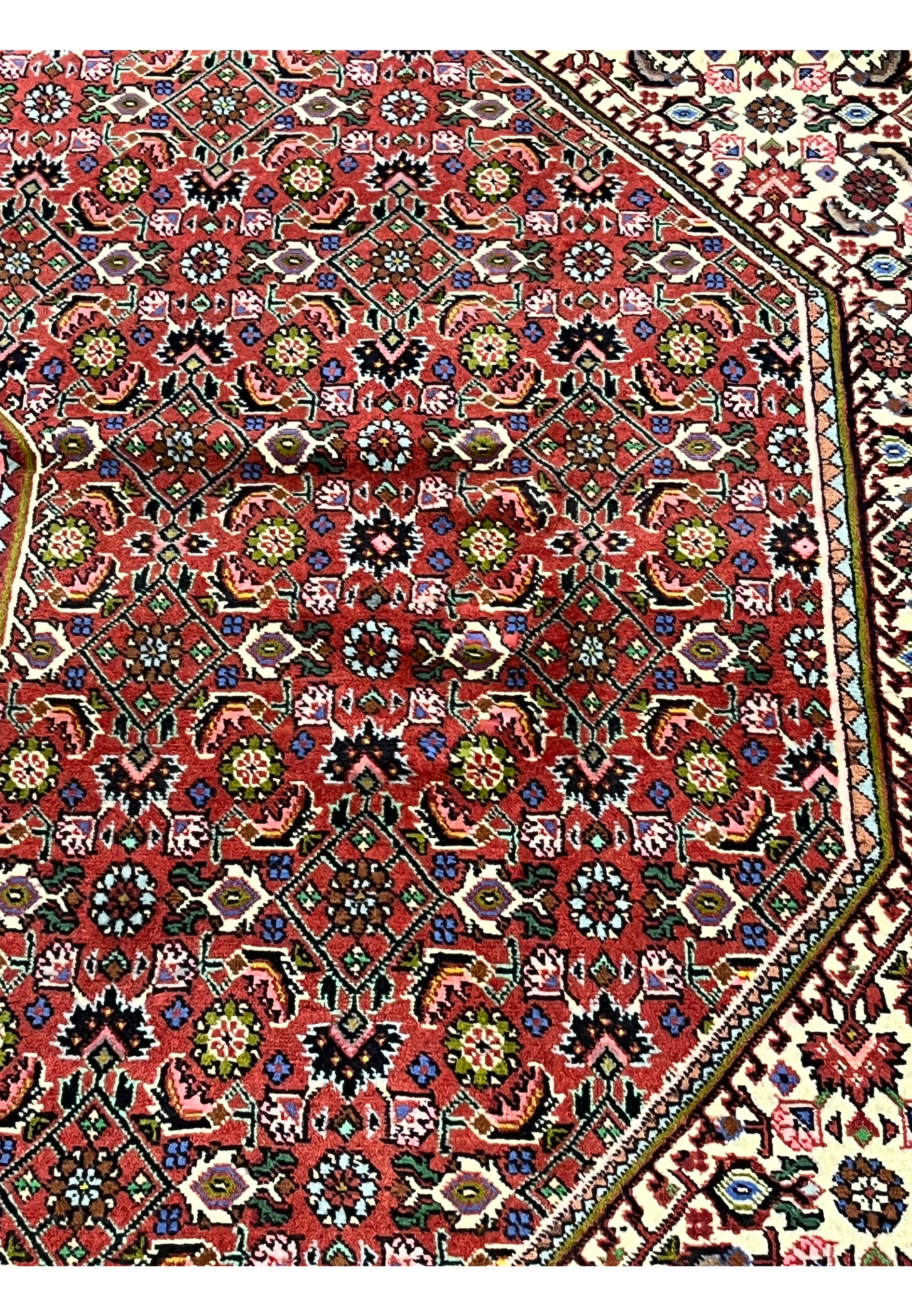 Brick red field detail of Persian Bijar rug showcasing dense geometric rosettes, vivid color saturation, and strong Kurdish design character