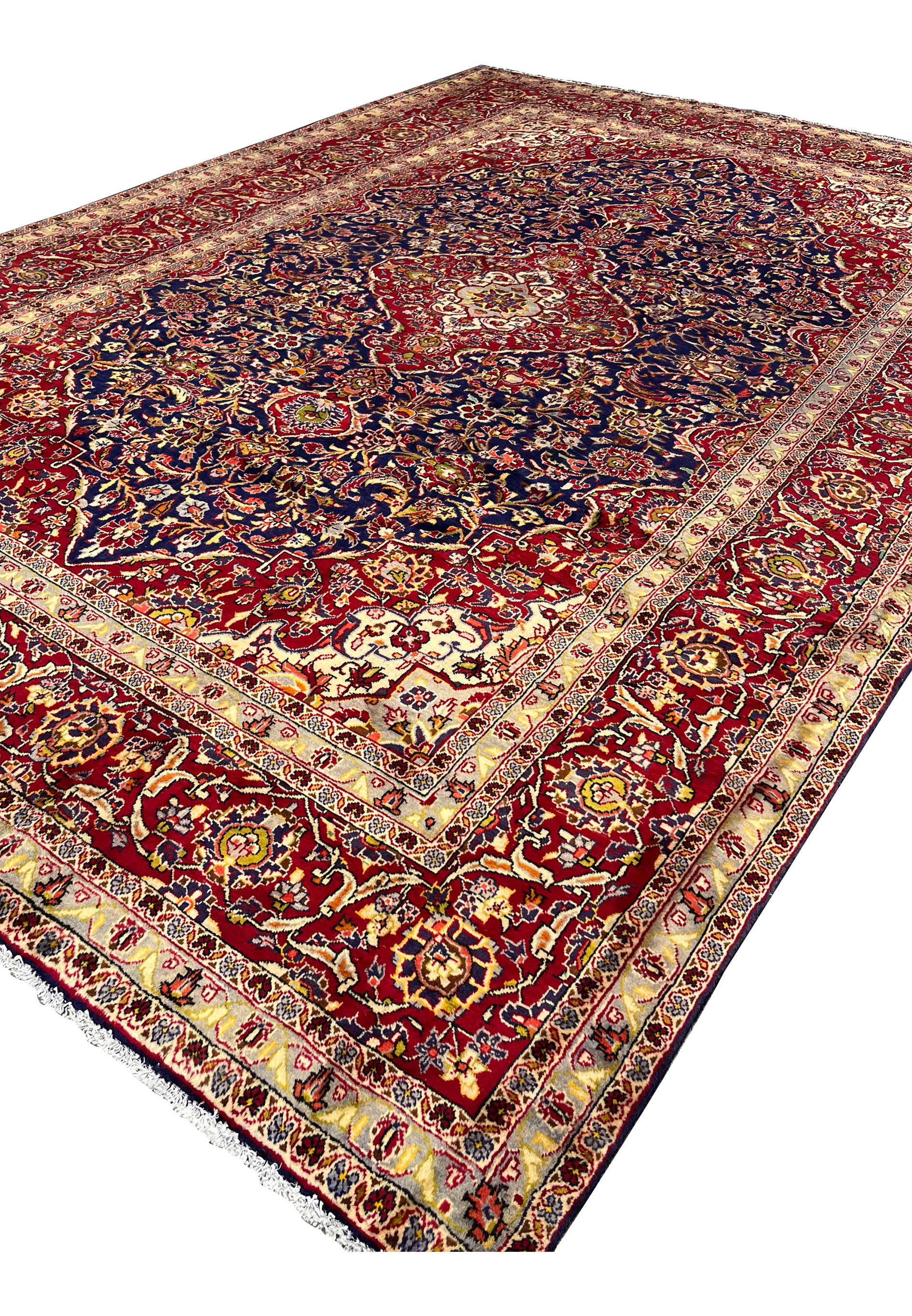 Angled perspective of Persian Isfahan rug displaying overall proportions, navy blue field depth, red medallion, and elegant border framing