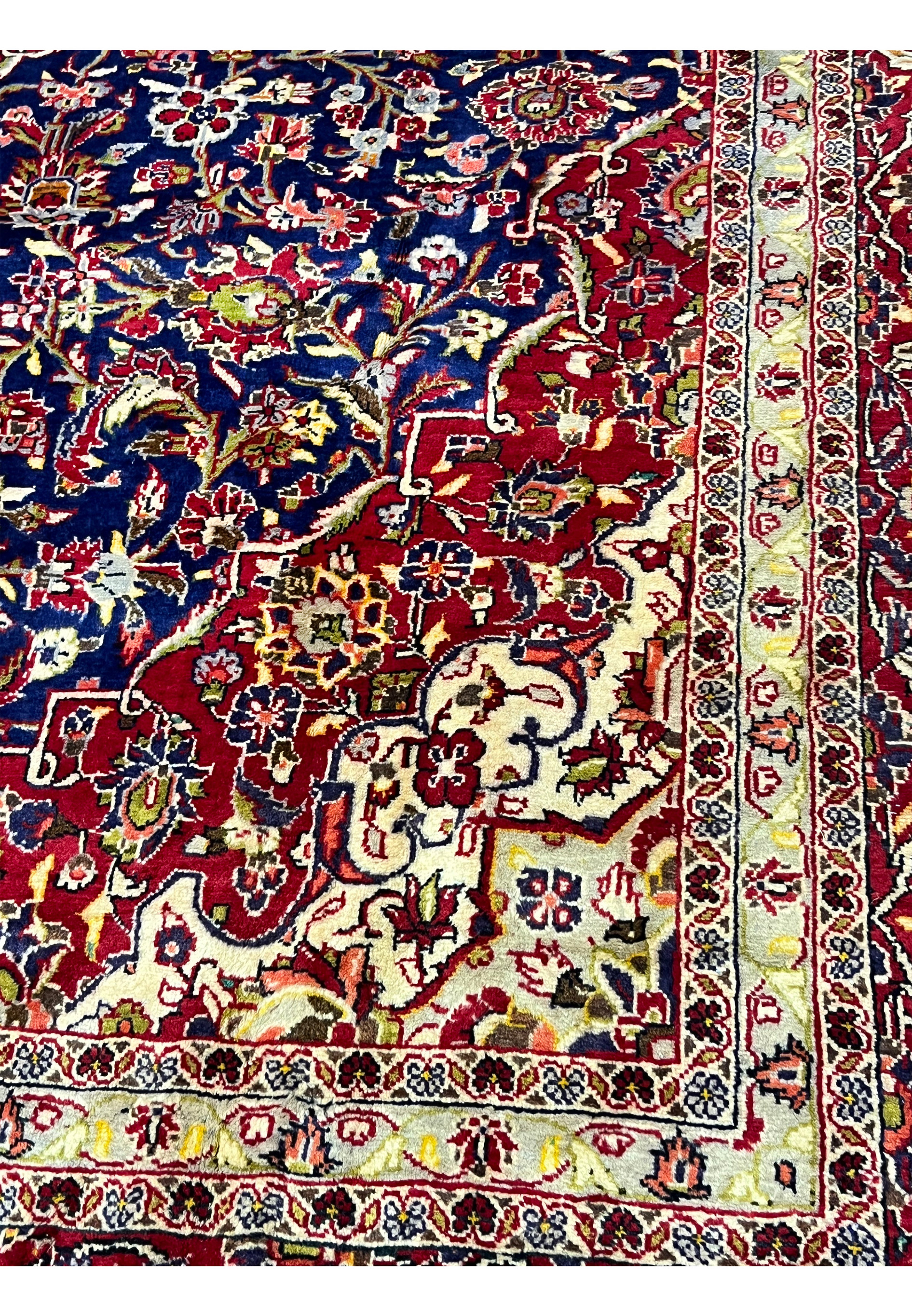 Lower inner field detail of Persian Isfahan rug featuring scrolling floral vines, navy background, ivory highlights, and subtle gold tones