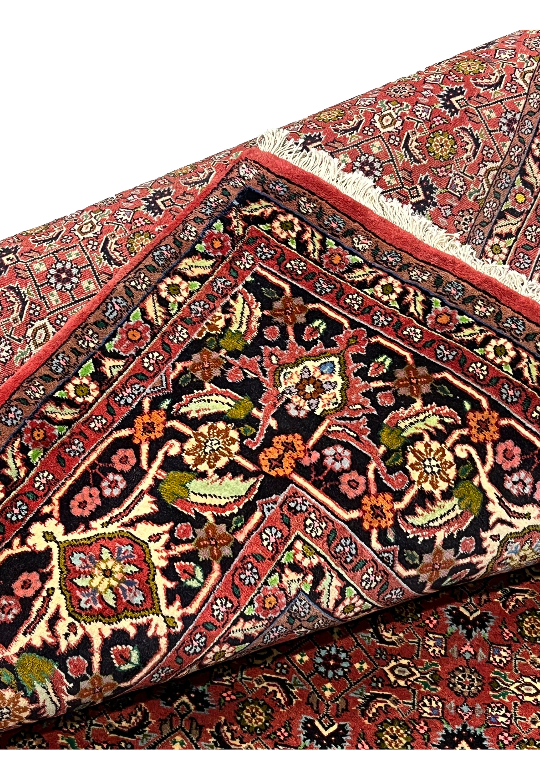 Folded edge of Persian Bijar rug revealing plush wool pile, crisp floral design, and flexible yet dense structure