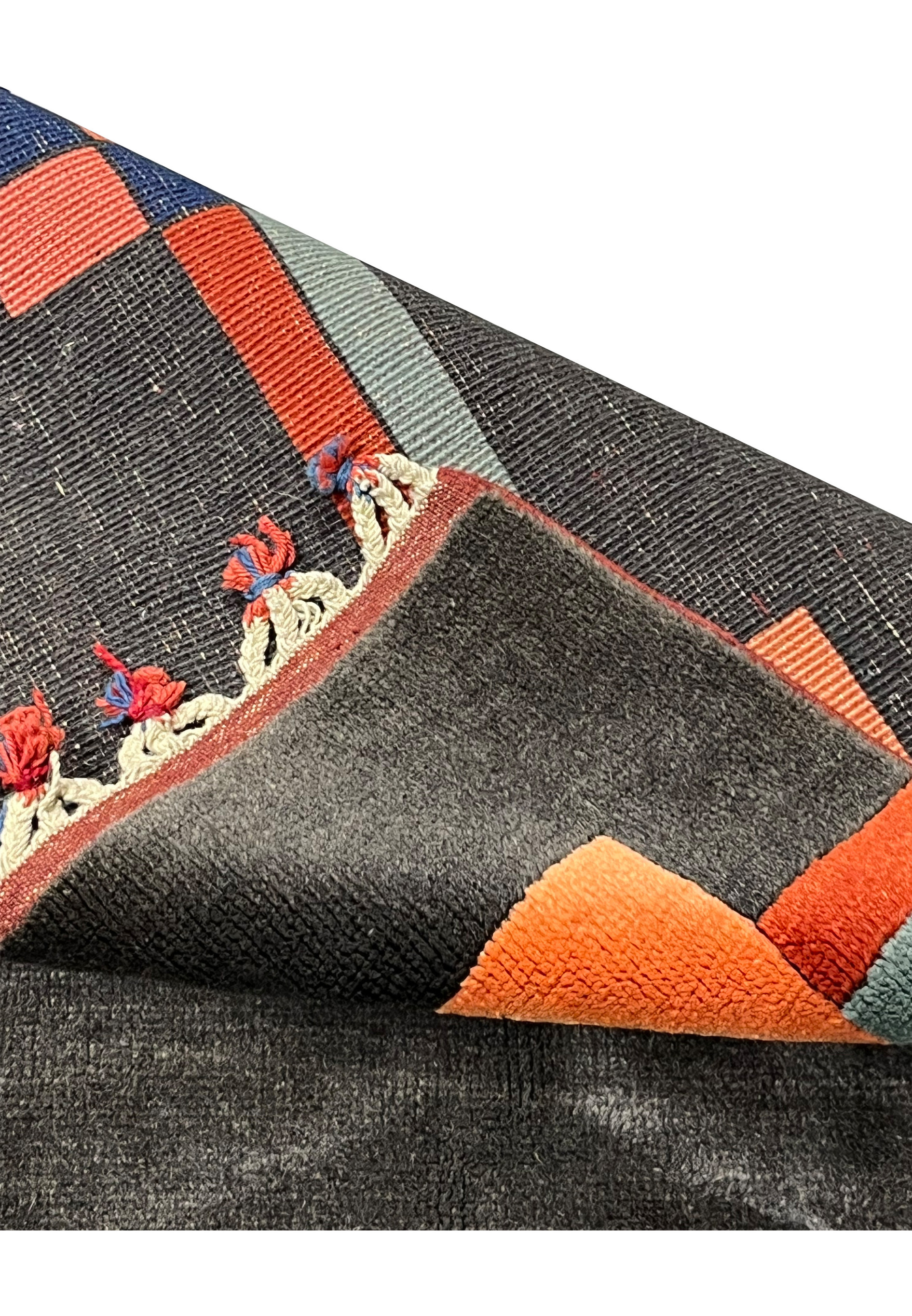 Folded corner close-up revealing pile density, soft wool texture, and color saturation of coral and charcoal tones