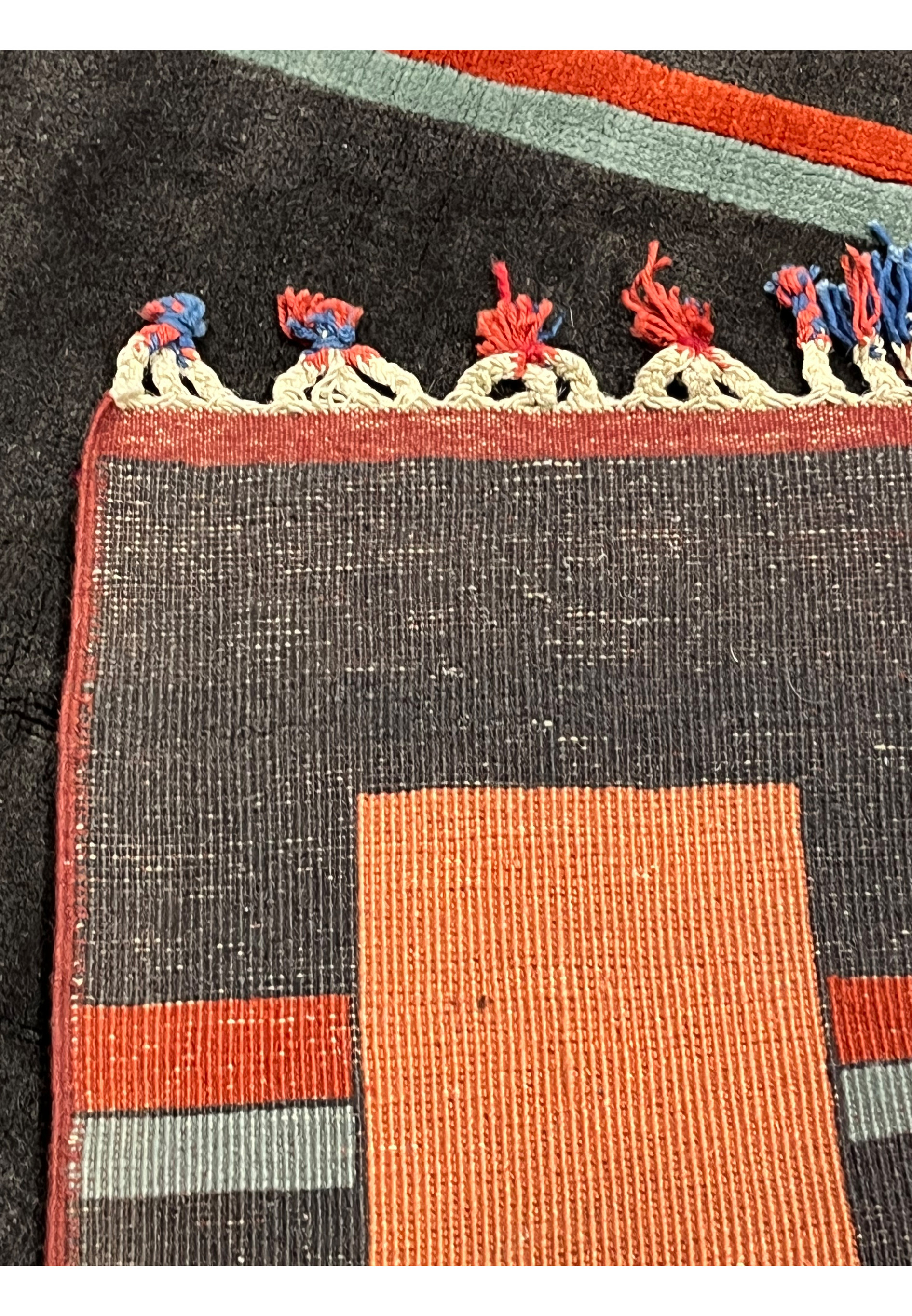 Backside of handmade Persian Gabbeh rug revealing dense wool foundation flat weave construction and red border stitching with tassels