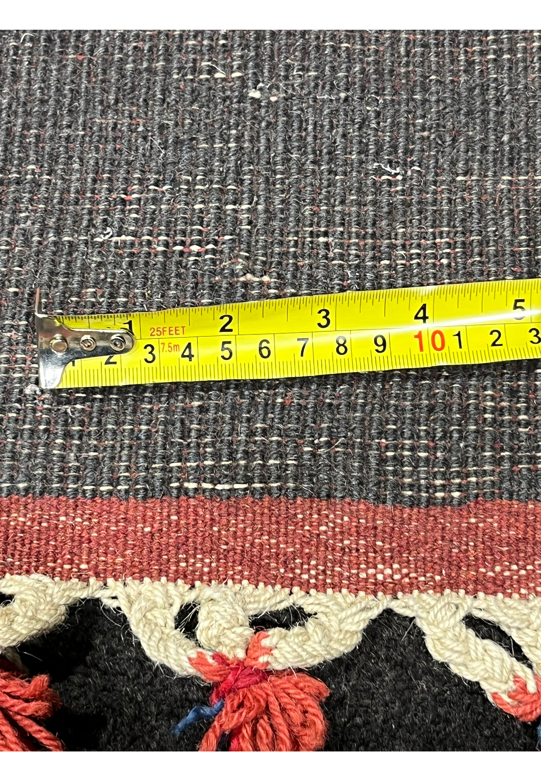 Back of Persian Gabbeh rug with measuring tape showing thickness and weave density handmade wool tribal construction with knotted fringe edge