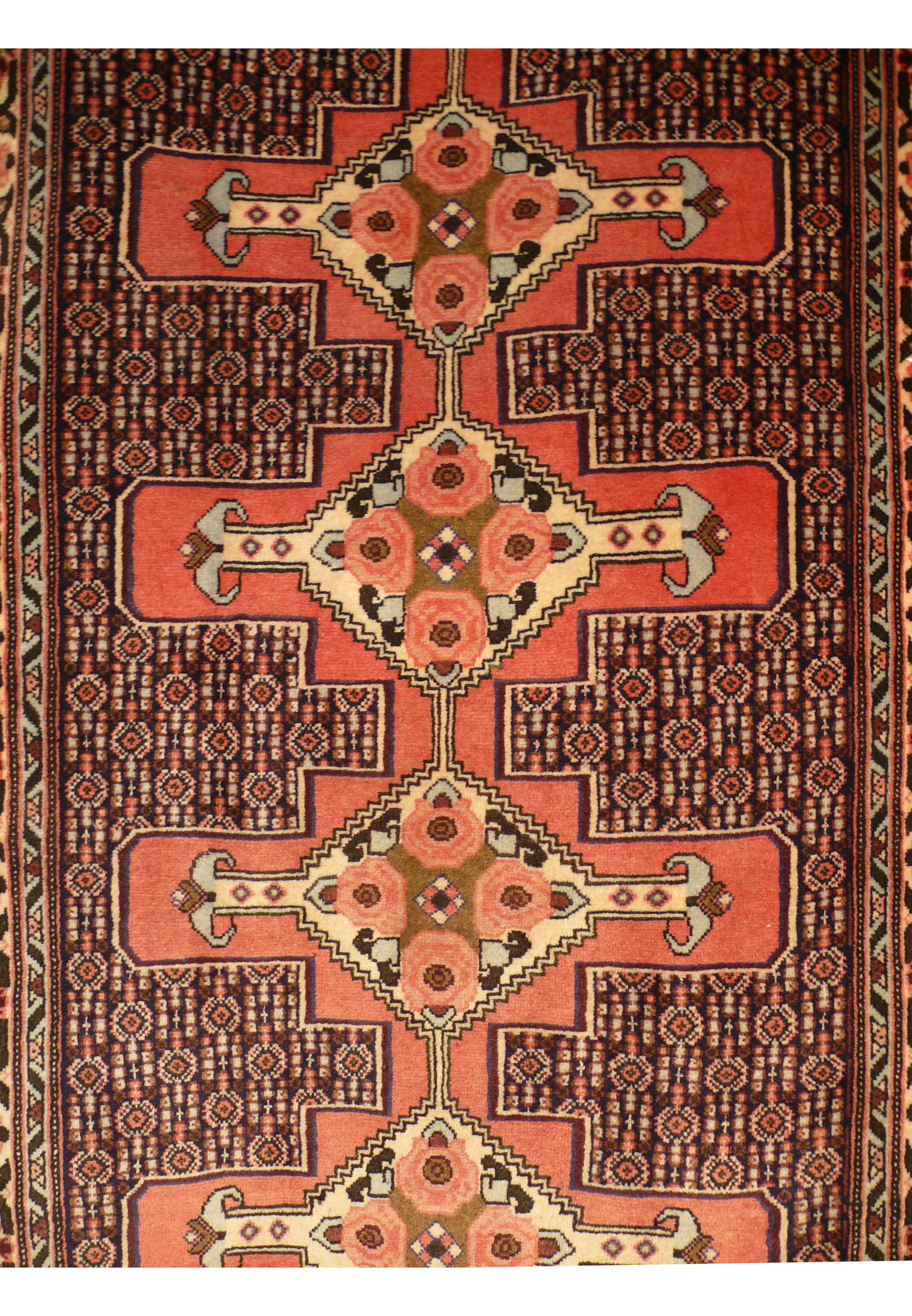 Detailed field section of handmade Persian runner with repeating boteh style forms and dense fine knot weaving