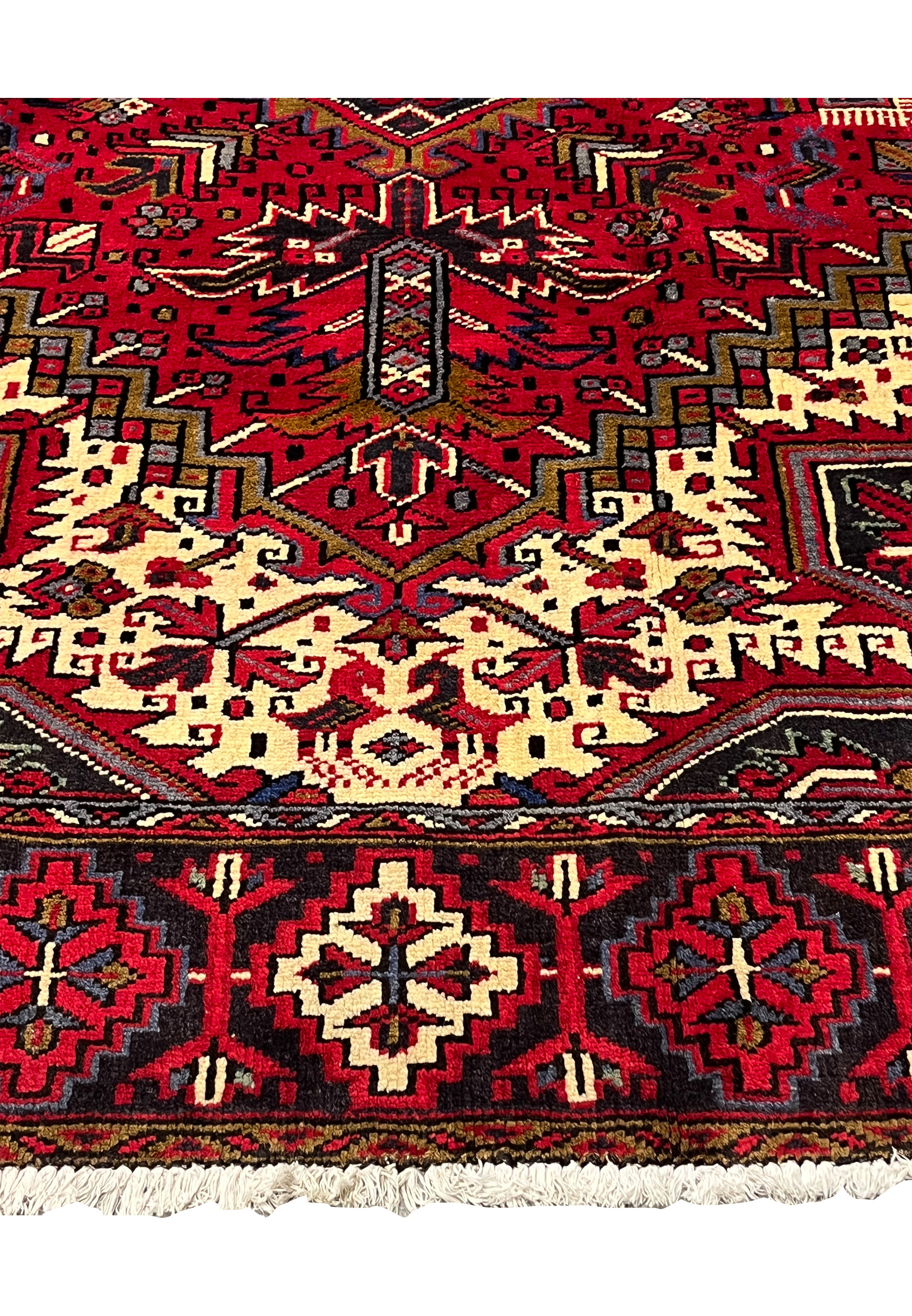 Lower border view of Persian Heriz rug with repeating geometric rosettes strong guard stripes and structured tribal framing