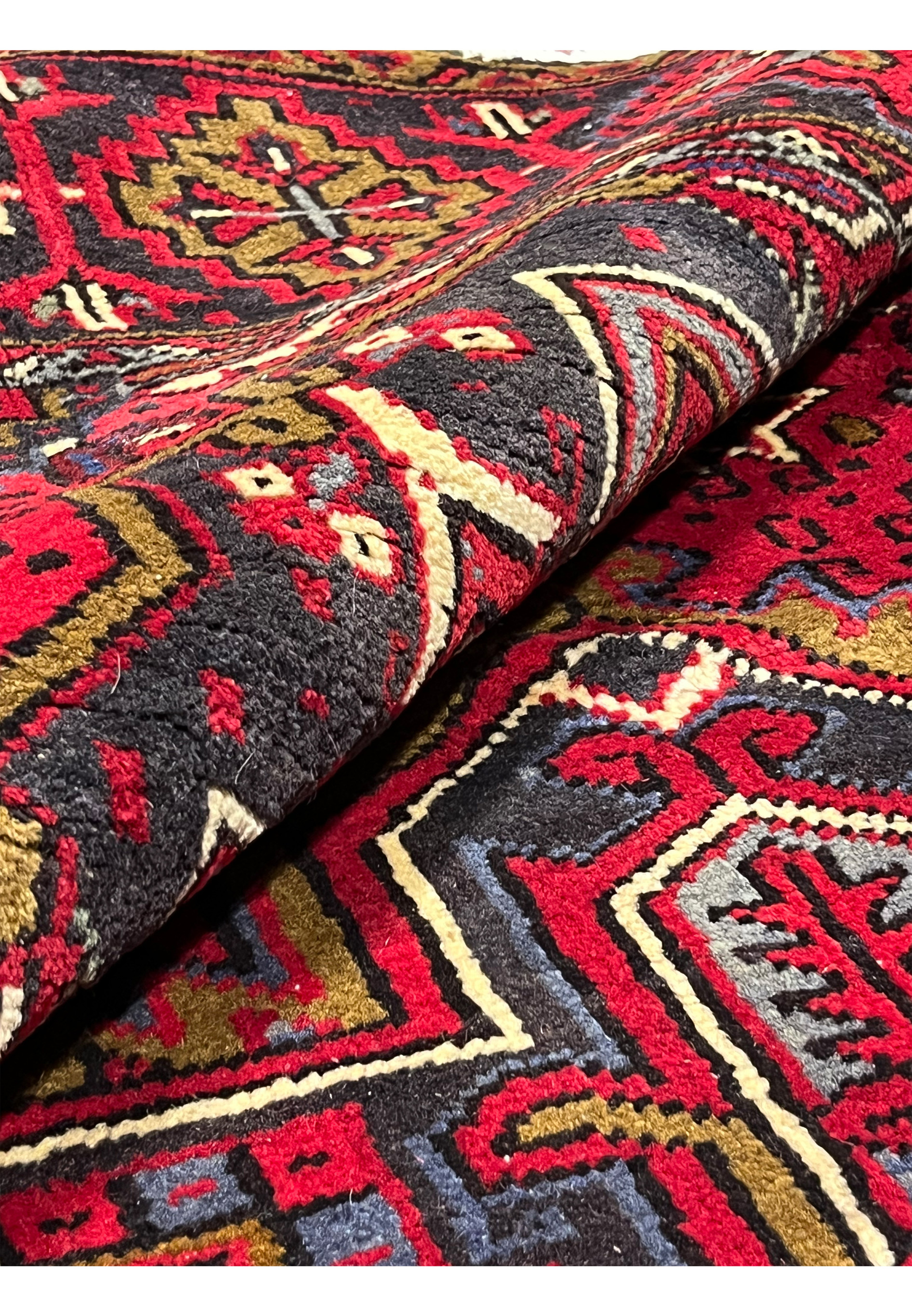 Rolled Persian Heriz rug displaying flexible wool body, dense pile thickness and sturdy hand knotted structure demonstrating durability and weight