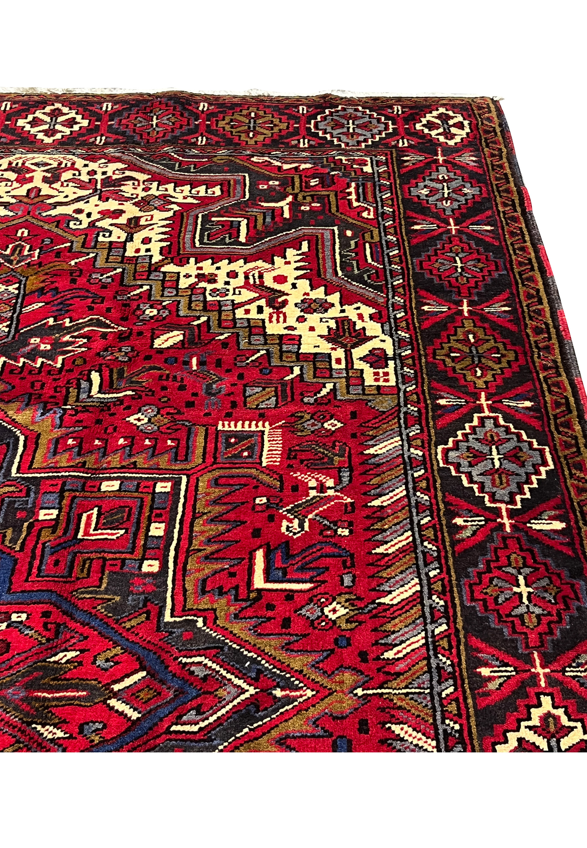 Upper border detail of handmade Heriz rug with repeating tribal rosettes, angular motifs and contrasting guard stripes in classic village design