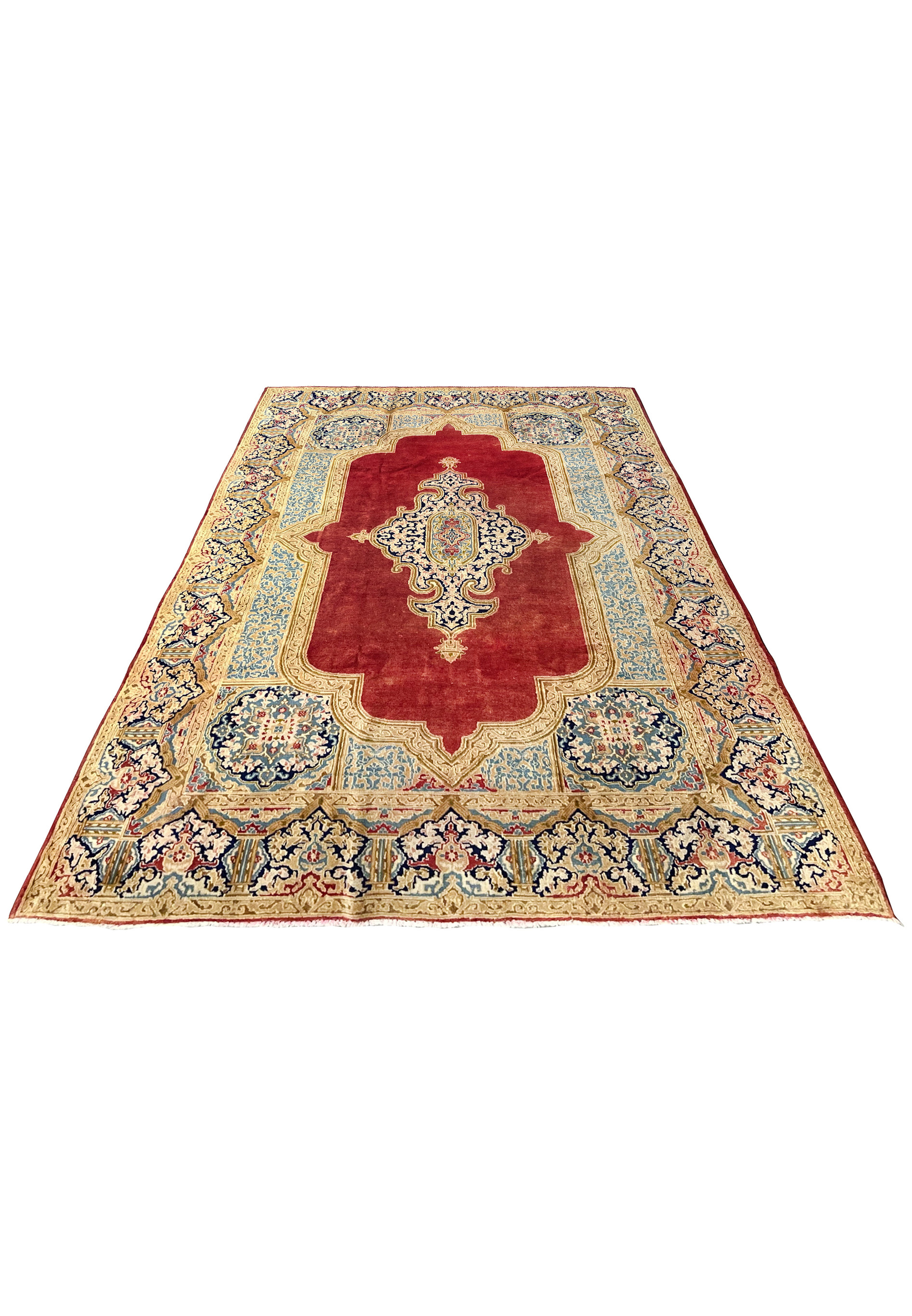 Laid down angle of vintage Persian Kerman rug showing soft wear patina floral field ivory border sky blue panels wool pile texture