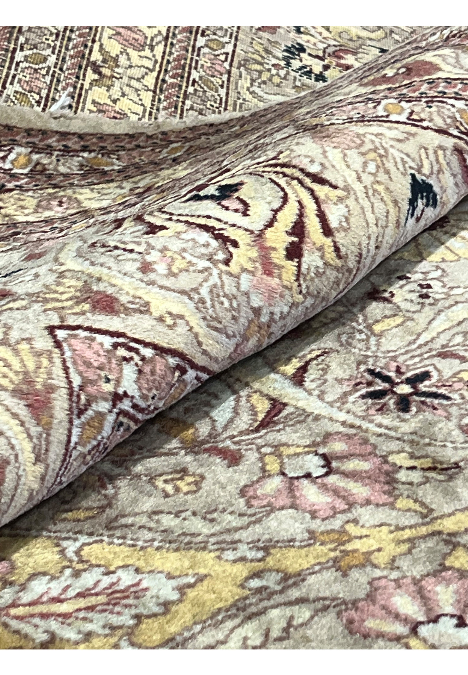 Rolled corner detail of handmade wool Agra rug showing pile thickness, flexibility, vintage wear, and soft beige gold floral weaving