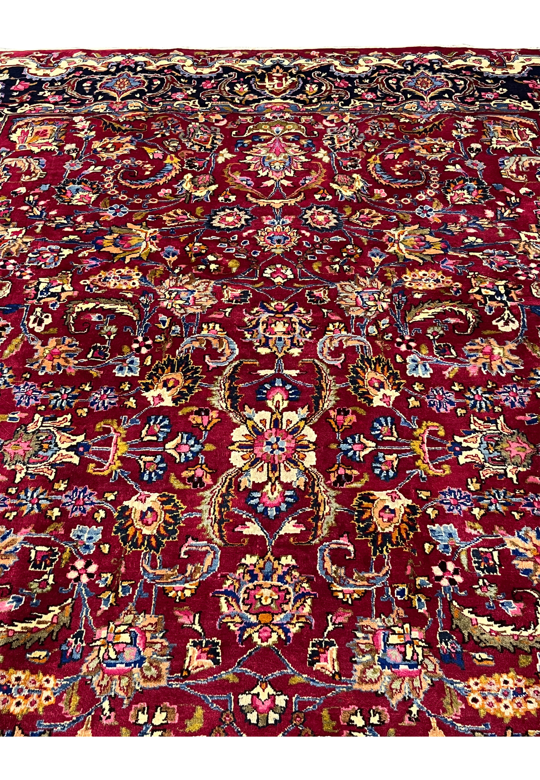 Close view of Mashad rug field showing dense floral arabesques, vibrant red background, and fine wool knotting