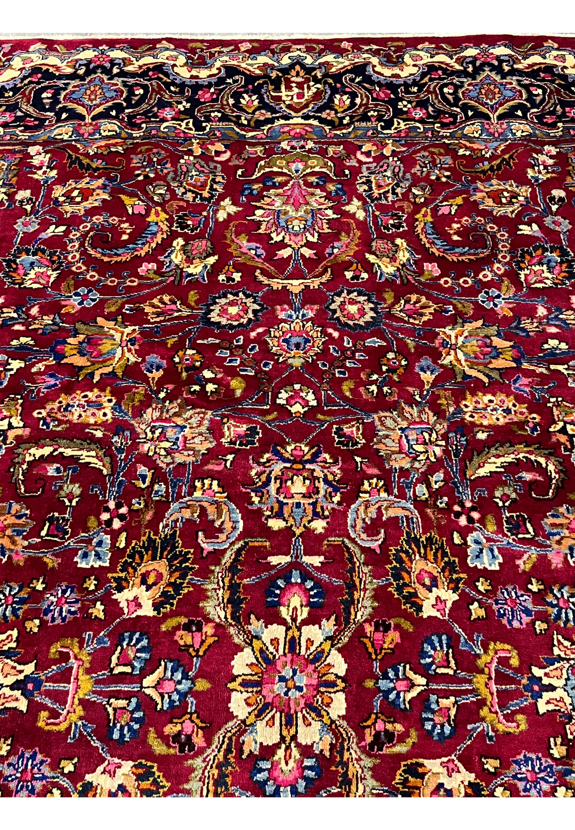 Close-up of floral motifs and scrolling vine patterns on 8x11 Persian Mashad rug, showing dense wool pile, vibrant reds, blues, and fine knot clarity