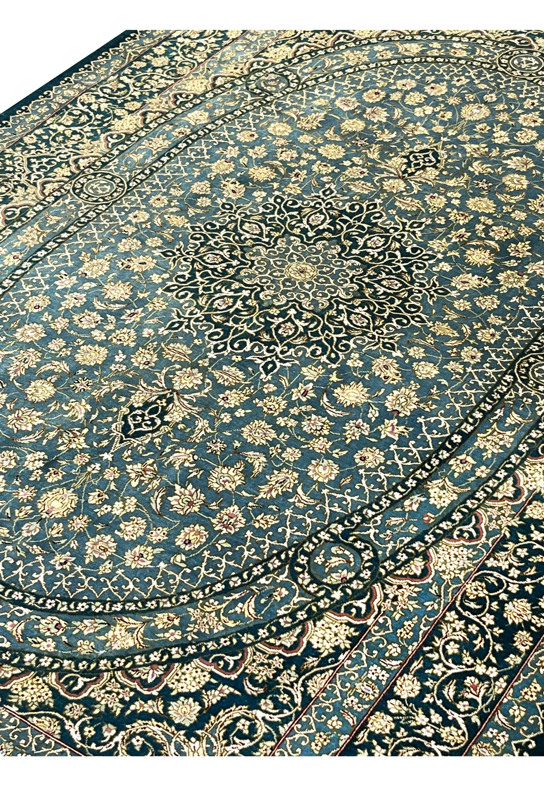Angled perspective of signed Darakhshan silk rug highlighting oval medallion, intricate floral field and reflective silk sheen under light