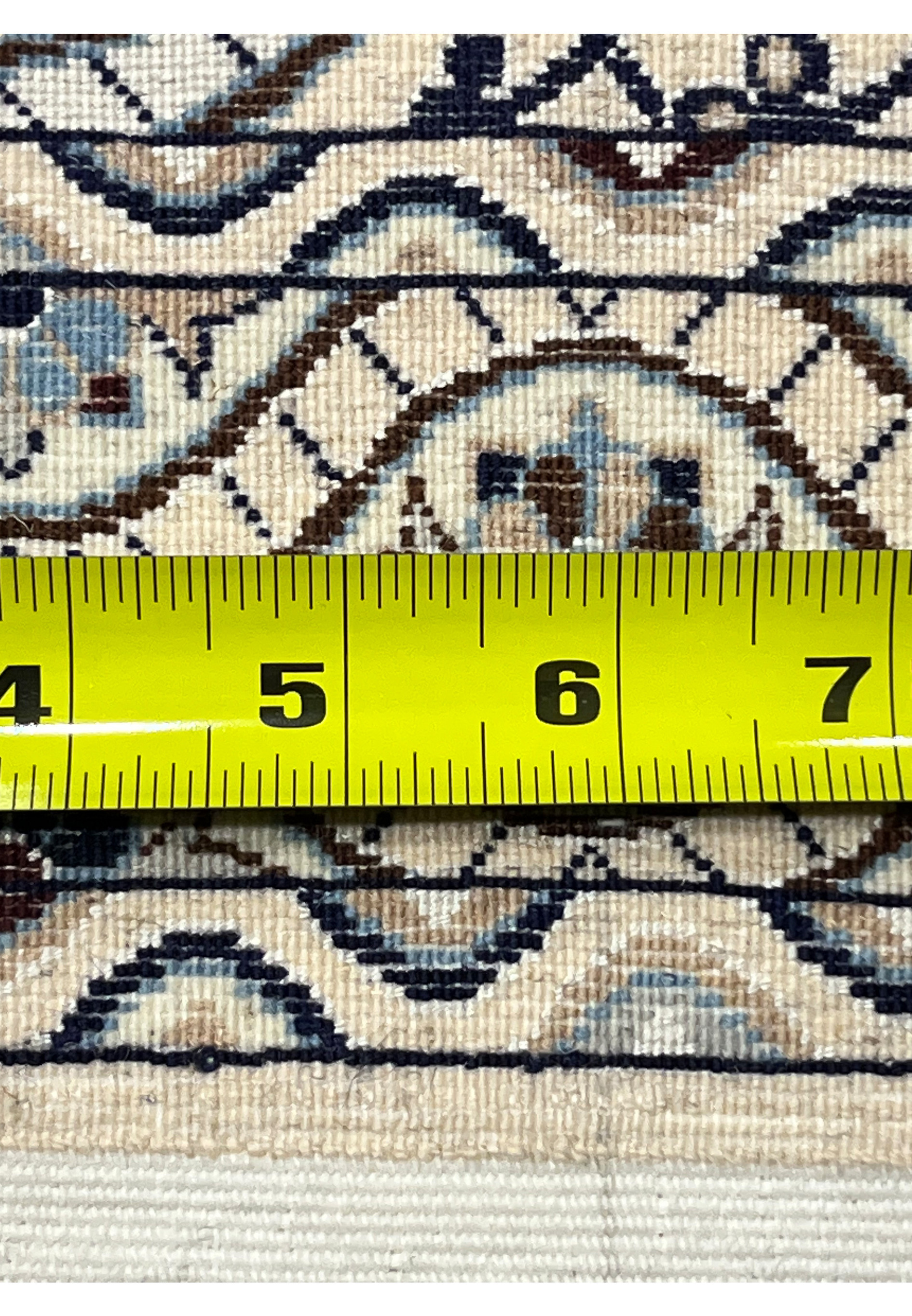 Back of Persian Nain 6 LA Habibian rug with measuring tape displaying tight knots ivory cotton base and precise weaving.