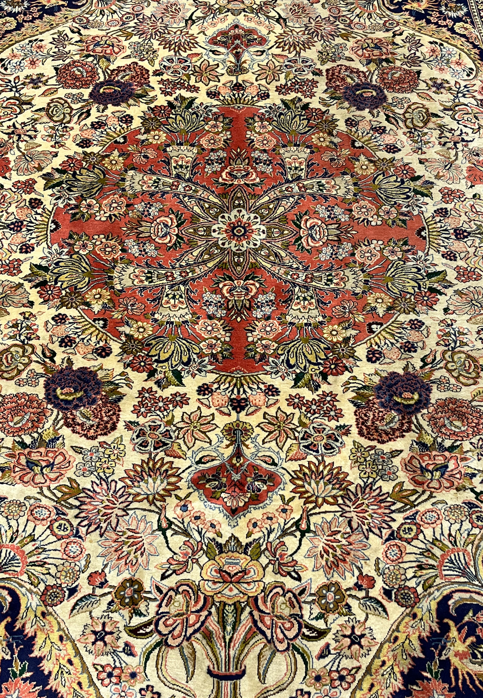 Close view of circular coral medallion with layered palmettes rosettes and ivory floral details on Persian Bijar rug