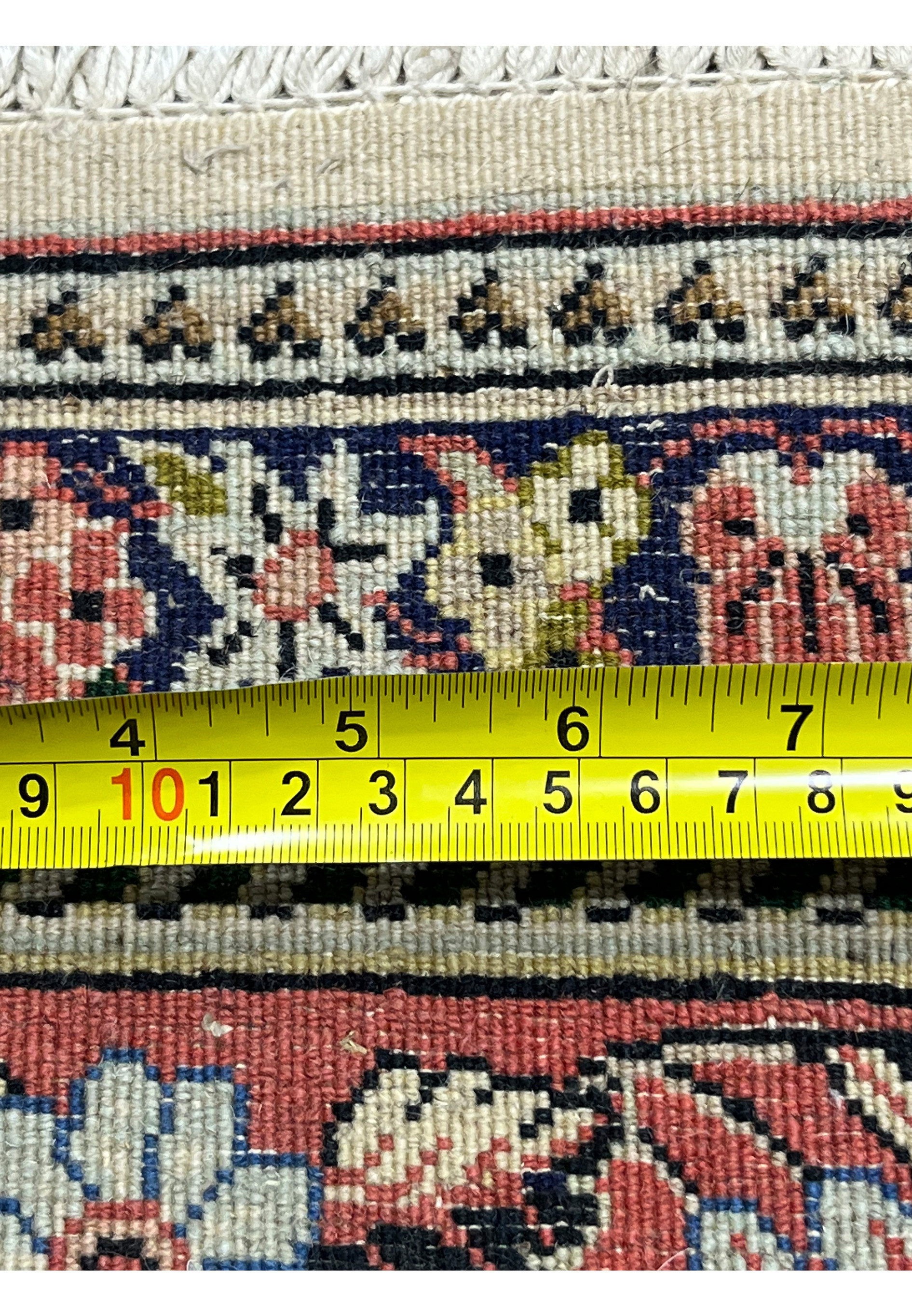 Zoomed backside of Persian Bijar rug with measuring tape showing tight knot density and compact weave
