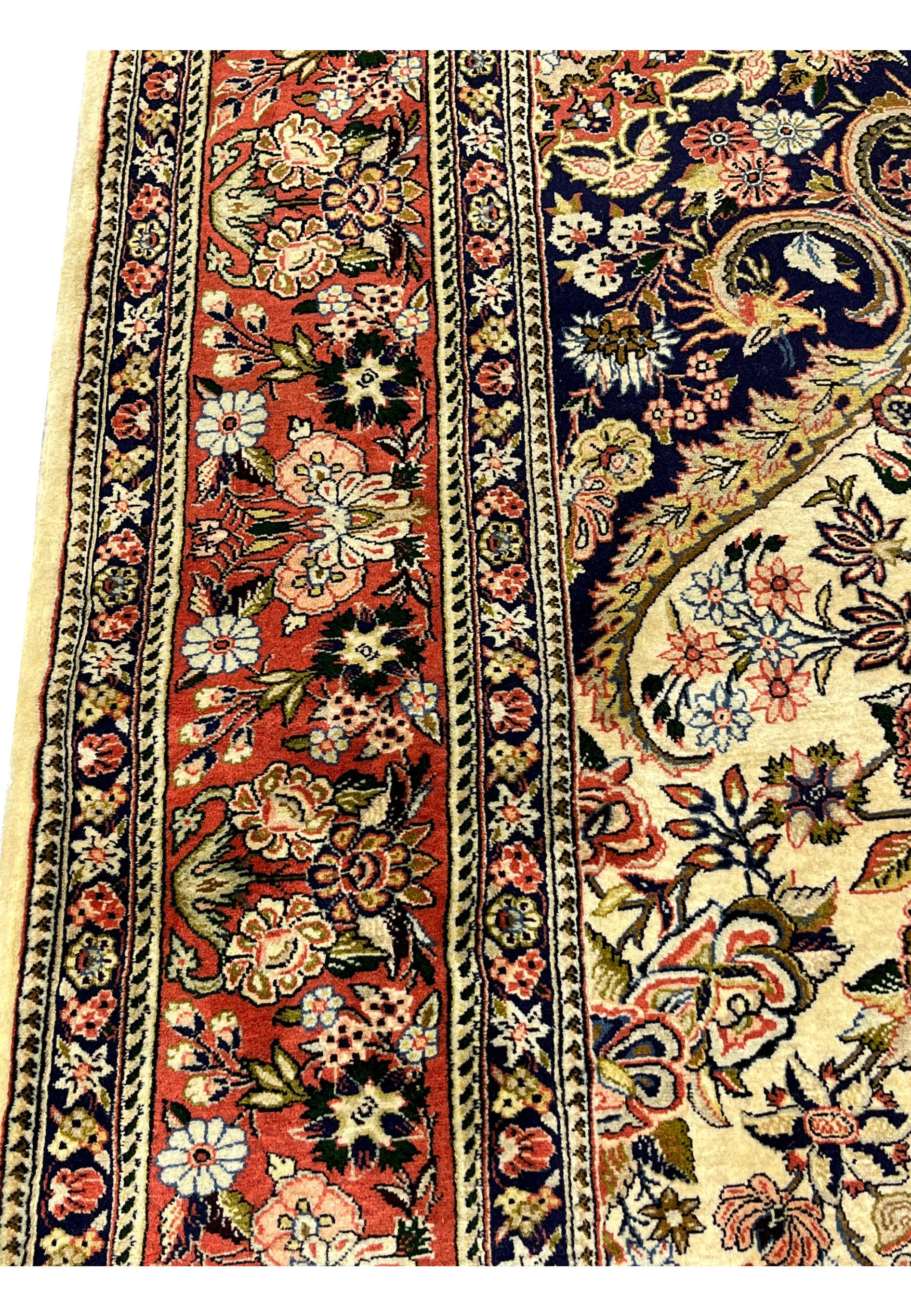 Closeup of wide coral border on Persian Bijar rug with scrolling vines palmettes and multicolor blossoms