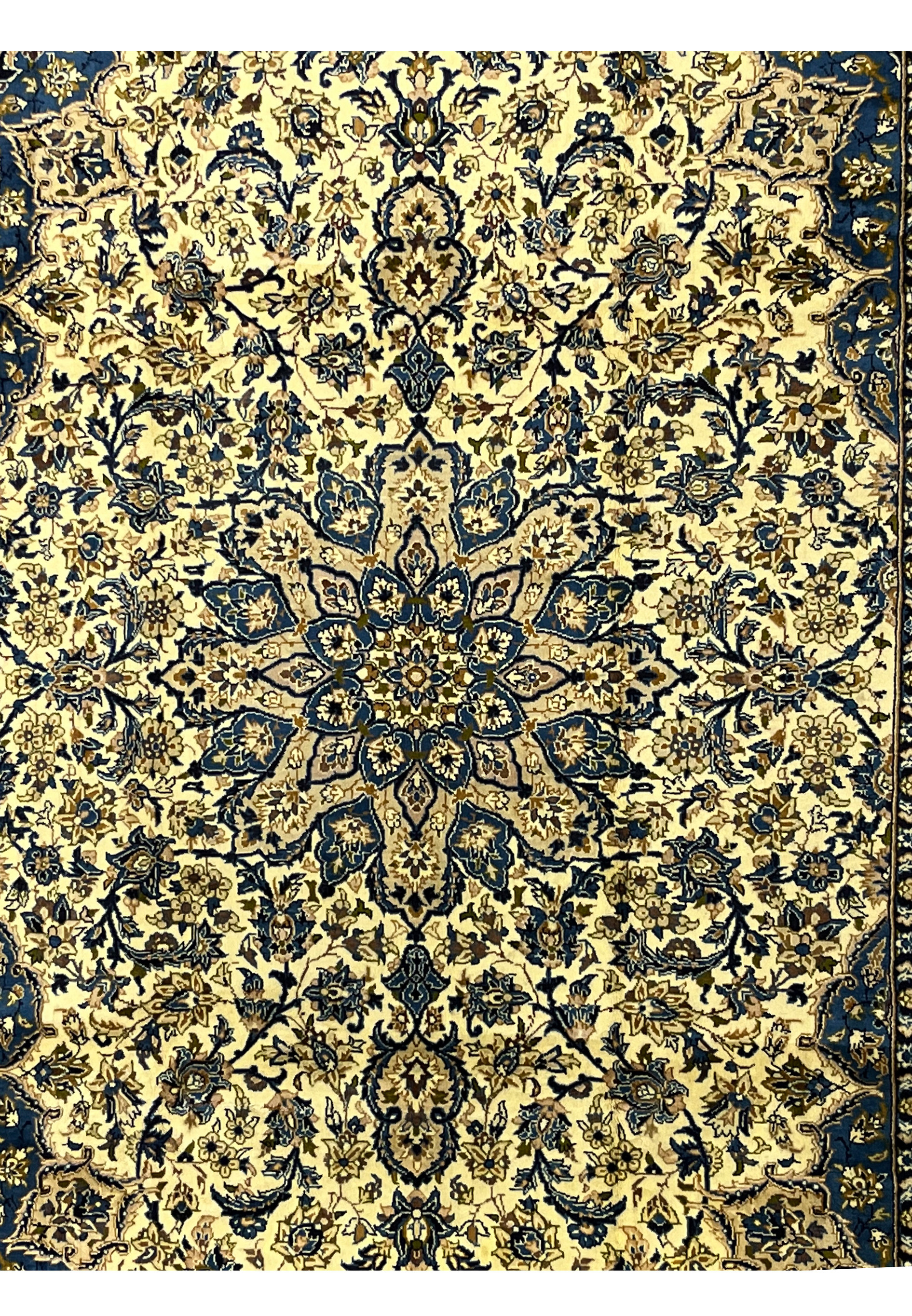 Central medallion detail of Persian Kashan rug in navy and gold tones layered floral rosettes on ivory ground