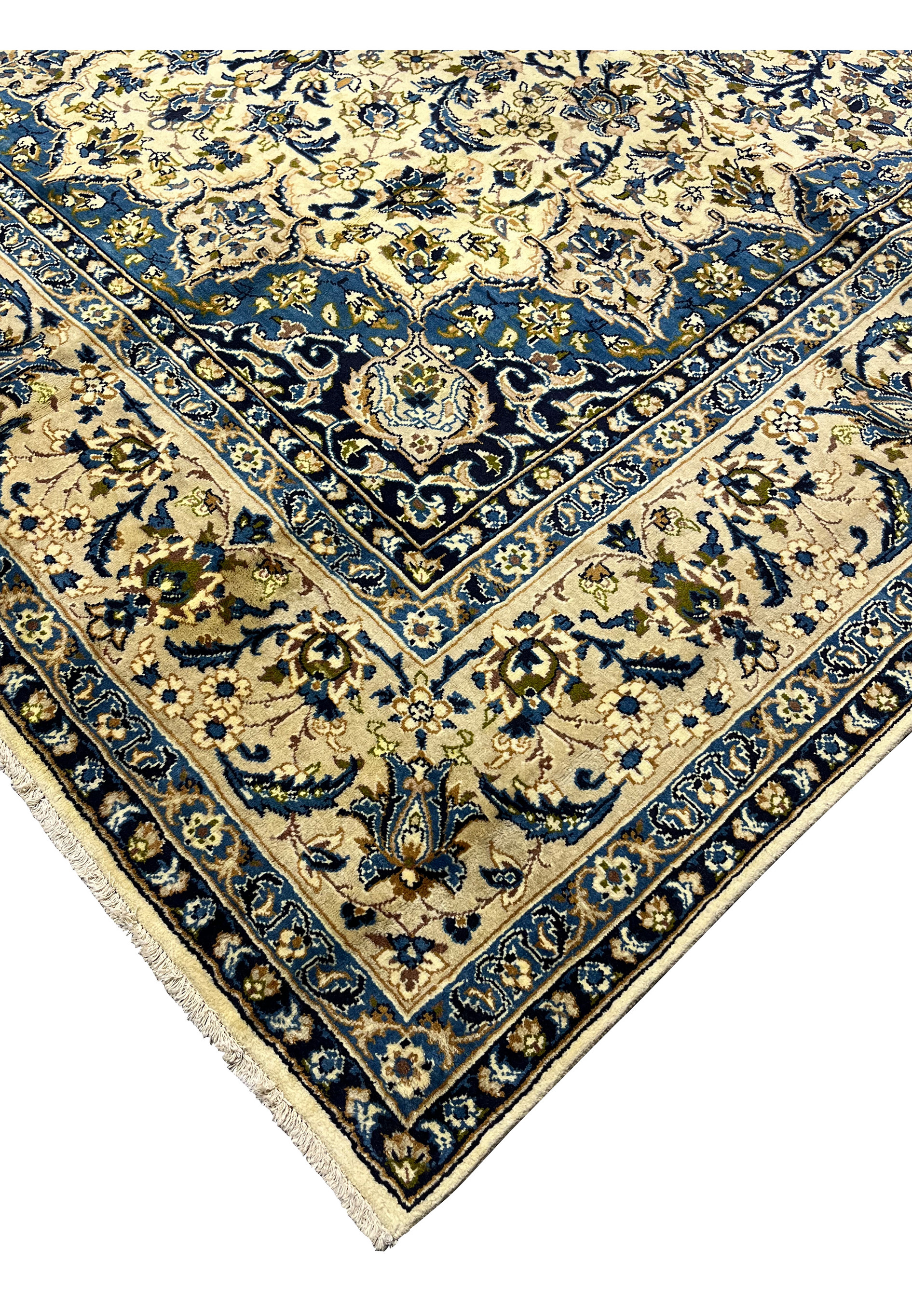 Edge detail of handmade Persian Kashan rug showing navy guard borders ivory field tight wool pile and finished fringe
