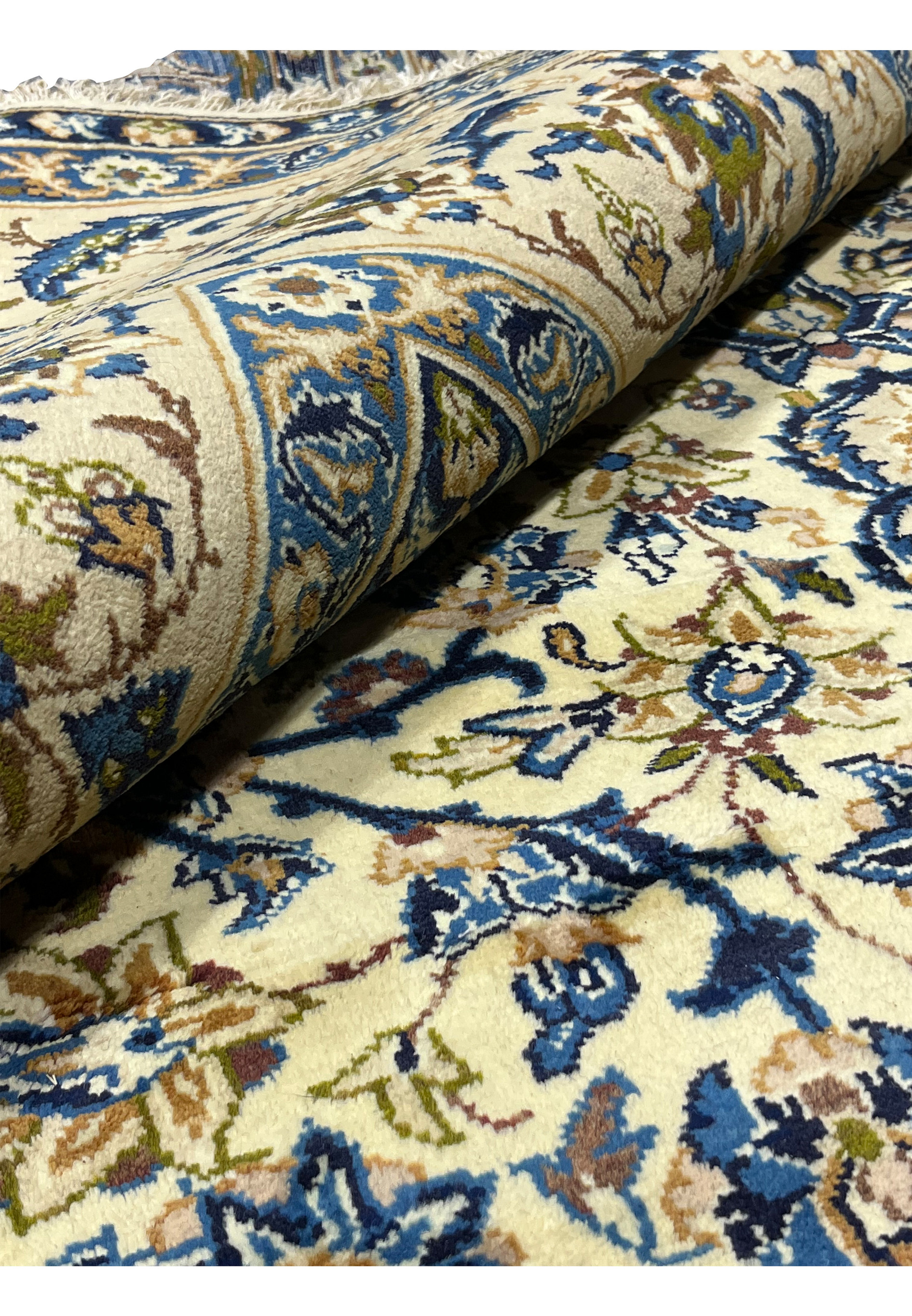 Rolled view of oversized 10'2 x 14'3 Persian Kashan rug showing ivory floral field navy border thickness and plush wool pile texture