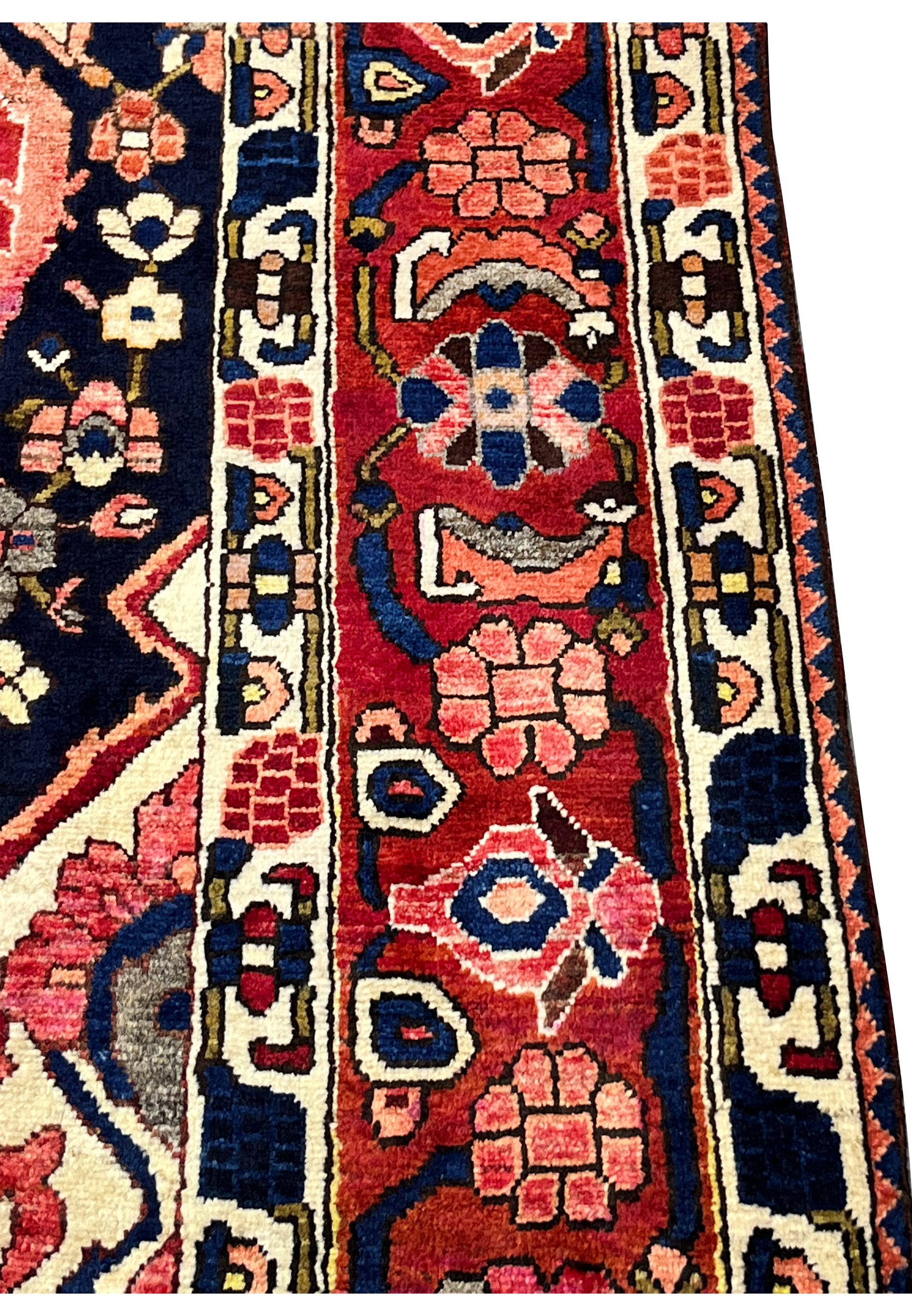 Close-up of main border on vintage Persian Bakhtiari rug with repeating floral heads on crimson red ground.