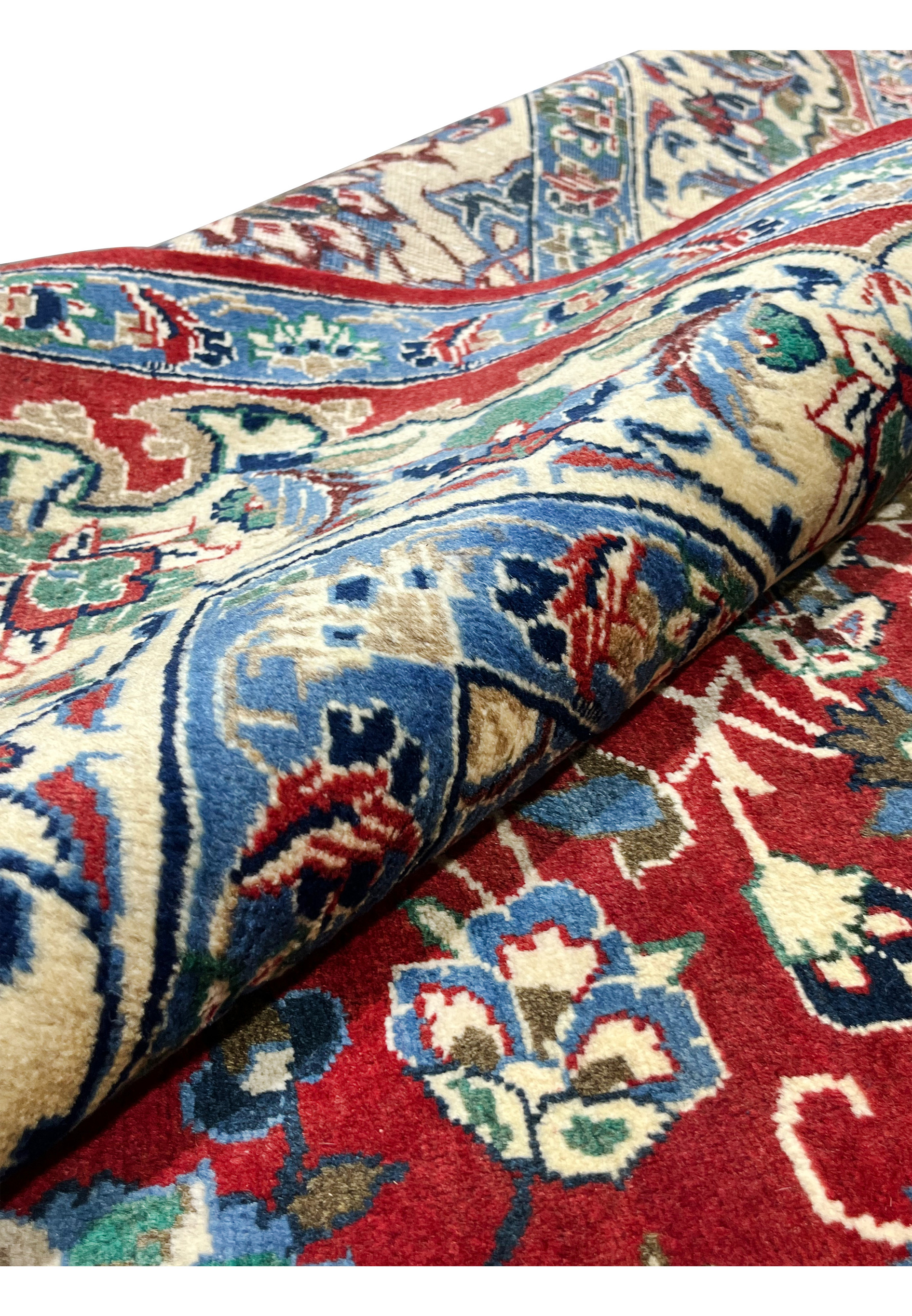 Rolled 8x12 Persian Isfahan wool rug showing pile depth blue ivory border floral design crimson red field handmade