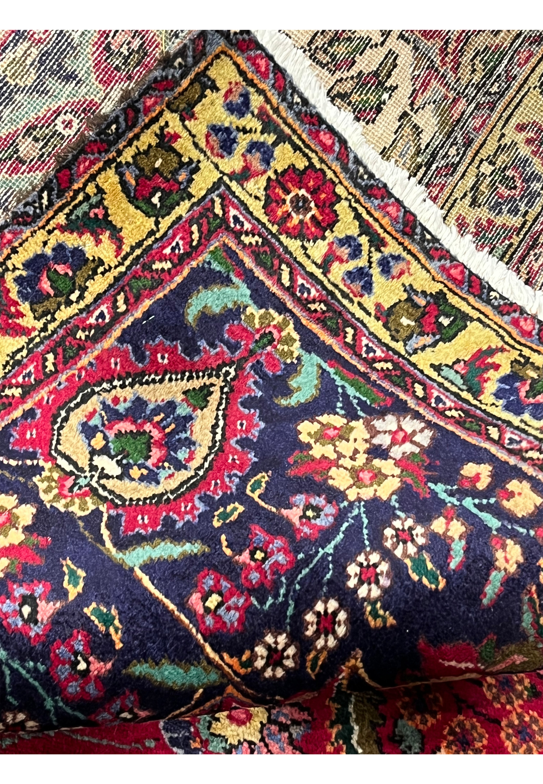 Folded edge of 10x13 Persian Tabriz rug showing back weave and front navy border