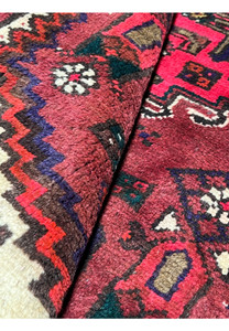 Rolled view of an antique Persian Hamedan rug highlighting thickness, flexible hand-knotted wool construction, and durable village weaving quality