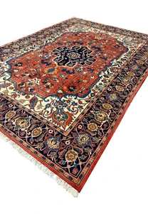 Angled perspective of a fine wool Persian Heriz rug highlighting pile texture, strong geometry, and rich red and navy colors