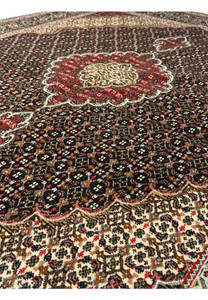 Lush texture and intricate pattern of a Persian Tabriz Mahi rug with a cream and red medallion set against a dark brown field, bordered in navy blue and ivory.