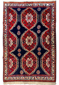 Full view of a traditional Qashqai rug displaying symmetric patterns and multiple borders, with dominant red and dark blue colors, and white fringes on the ends