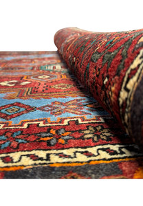 Partial view of a Persian Gholtogh Rug focusing on the geometric shapes and the interplay of warm and cool tones