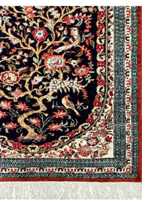 Edge of the Persian Qum silk rug, highlighting the tight weave, fringe details, and contrasting border colors