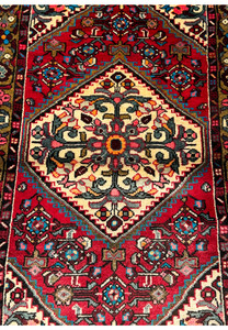 Close-up of the central medallion and floral patterns on a Persian Hamedan rug against a crimson background