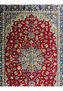 A detailed view of the Persian Isfahan rug's central design, focusing on the dense floral patterns and the ornate medallion with its complex layering of blue, gold, and cream on a rich red base