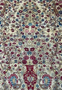 A close-up of the central part of the rug, highlighting the detailed vases and tree of life motif amidst the floral patterns.