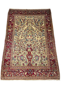 The Antique Persian Farahan rug presented at an angle, emphasizing its lush floral design and intricate border detail